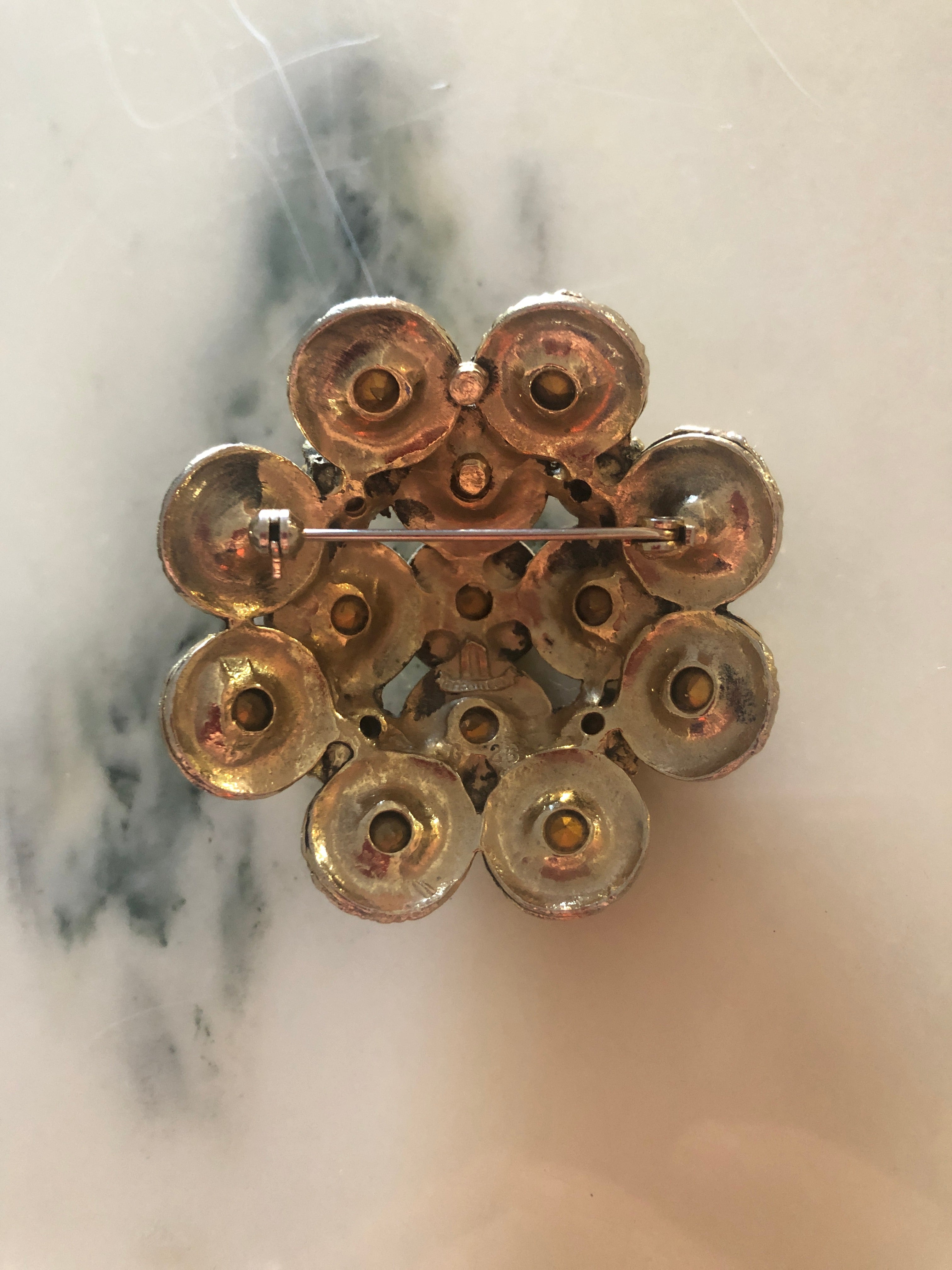 A vintage signed Elizabeth Reimer Éclat d'Ambre Paris silver-tone cluster brooch featuring graduating layers of faceted round champagne and amber crystal rhinestones in ornate individual settings, forming a domed floral cluster arrangement, photographed on a white marble surface.