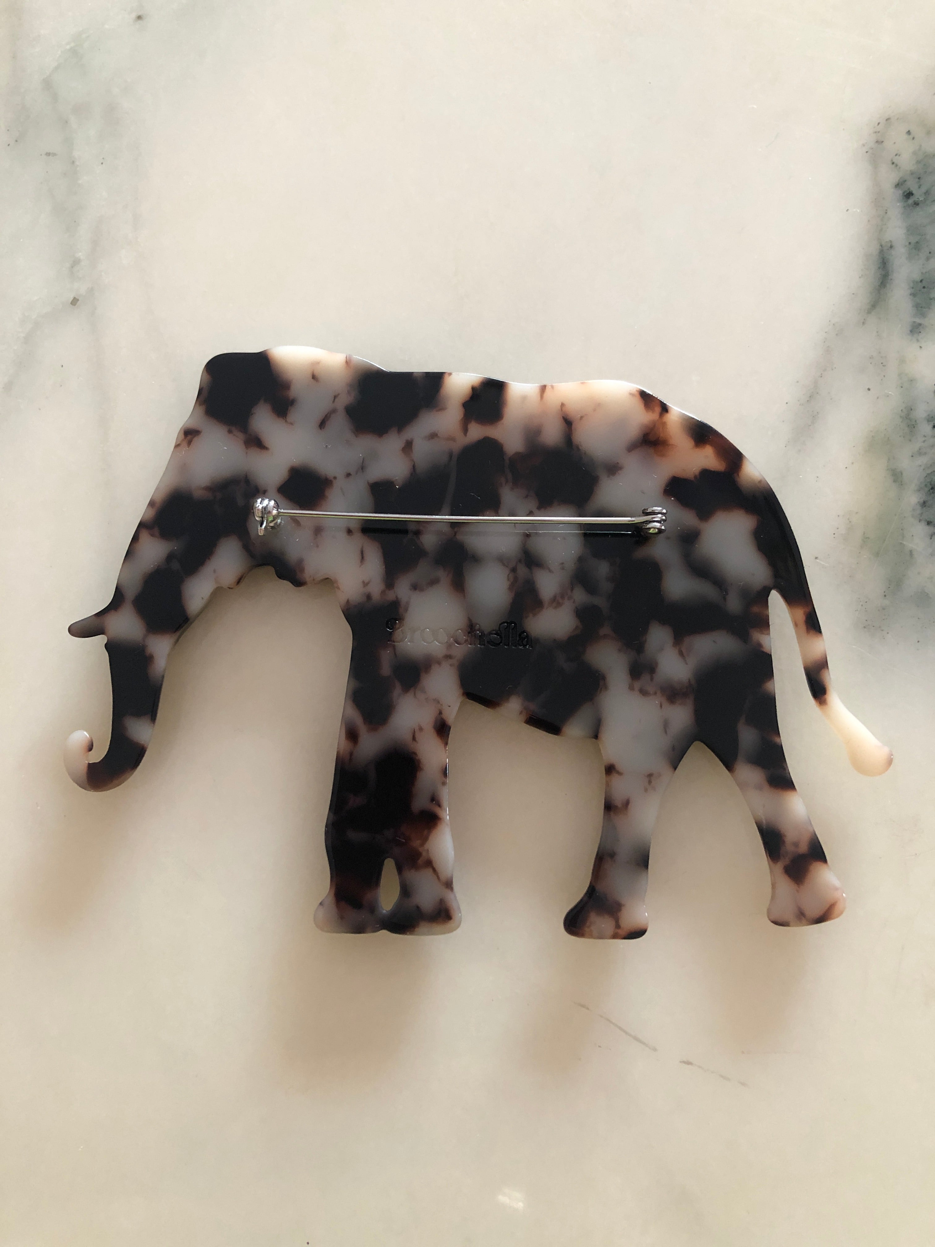 Men's elephant brooch in brown tortoiseshell acetate. Pictured on a white marble background