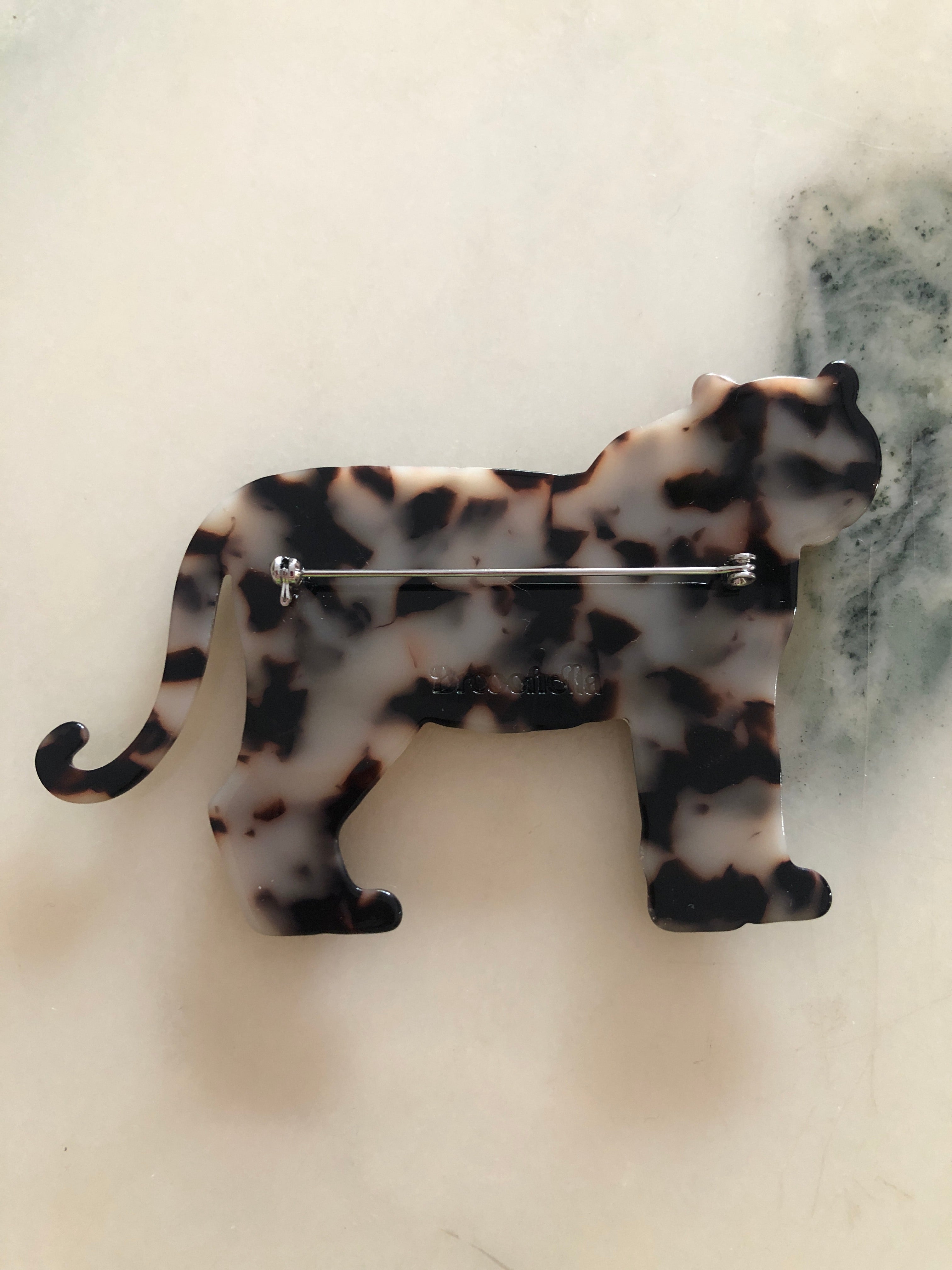 Men's tiger brooch in brown tortoiseshell acetate. The background is white marble