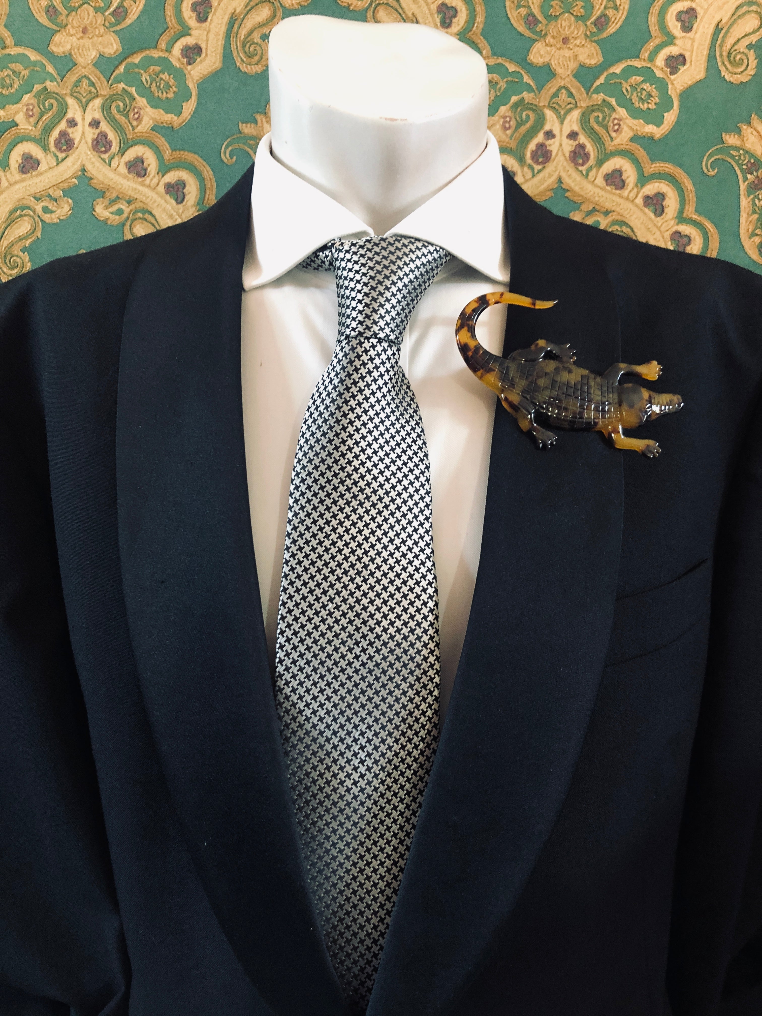 Men's alligator brooch in brown tortoiseshell acetate worn on a black tailored jacket with silver houndstooth tie, from the Broochella Animalia Collection.