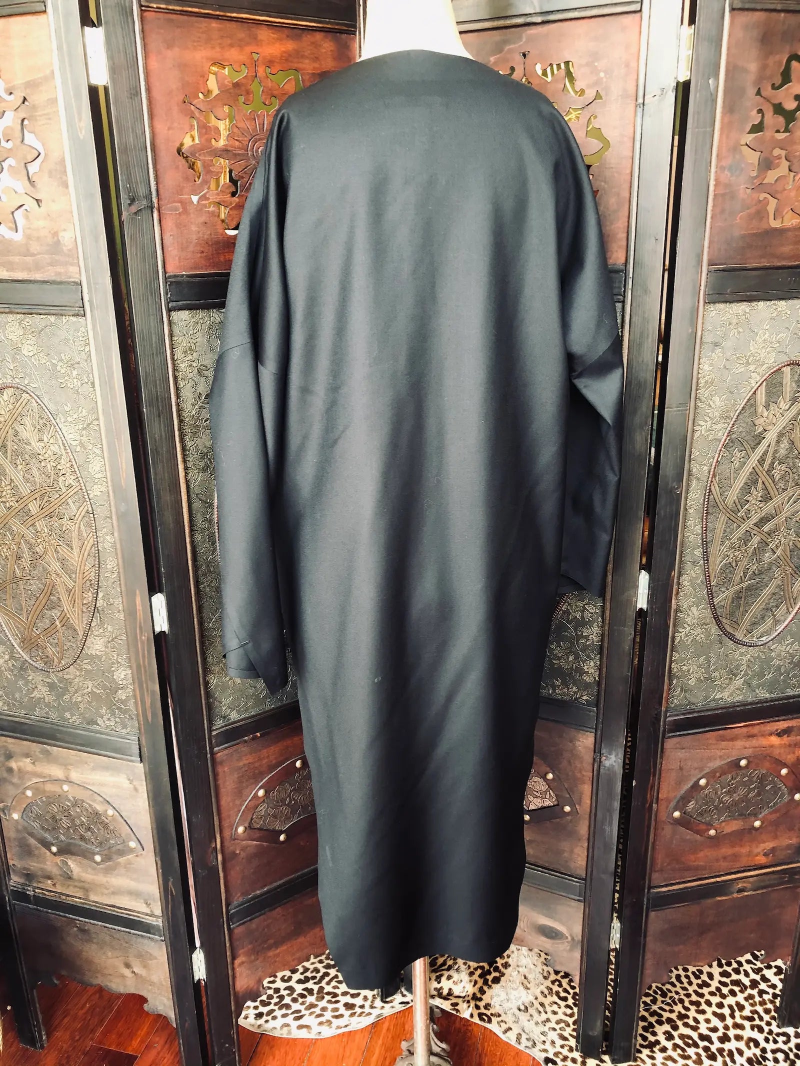 Broochella Barbara Alan Black back view of a dress on a mannequin in front of a decorative wooden screen. 