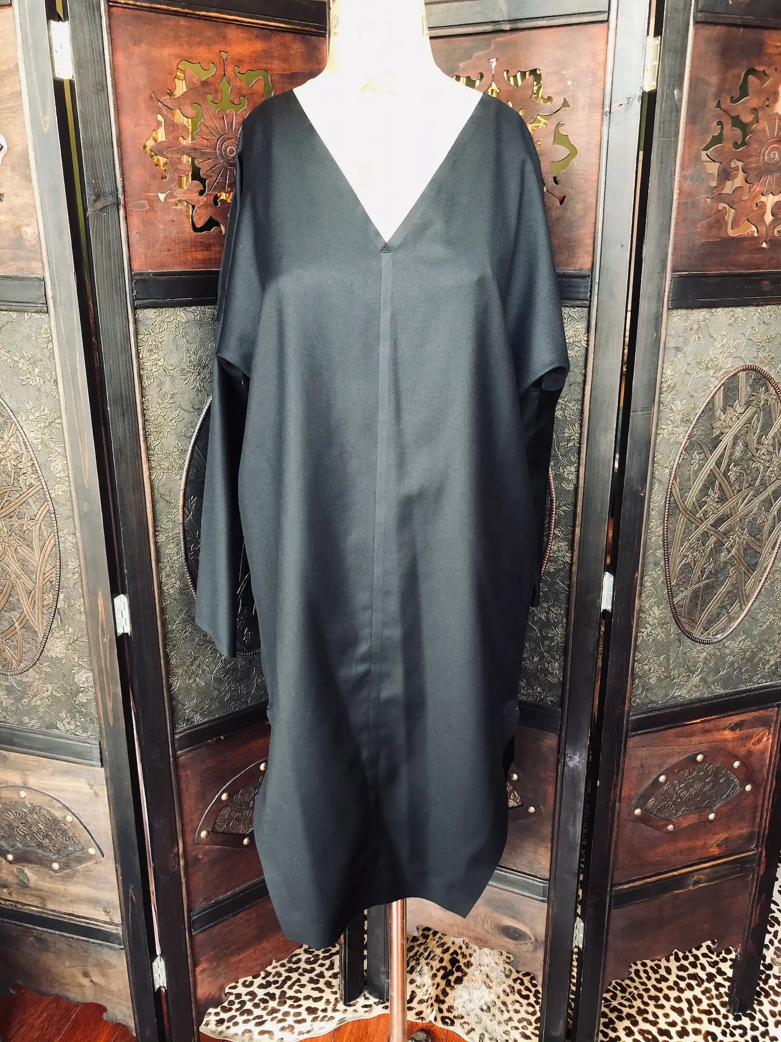 Broochella Barbara Alan Black dress on a mannequin in front of a decorative wooden screen