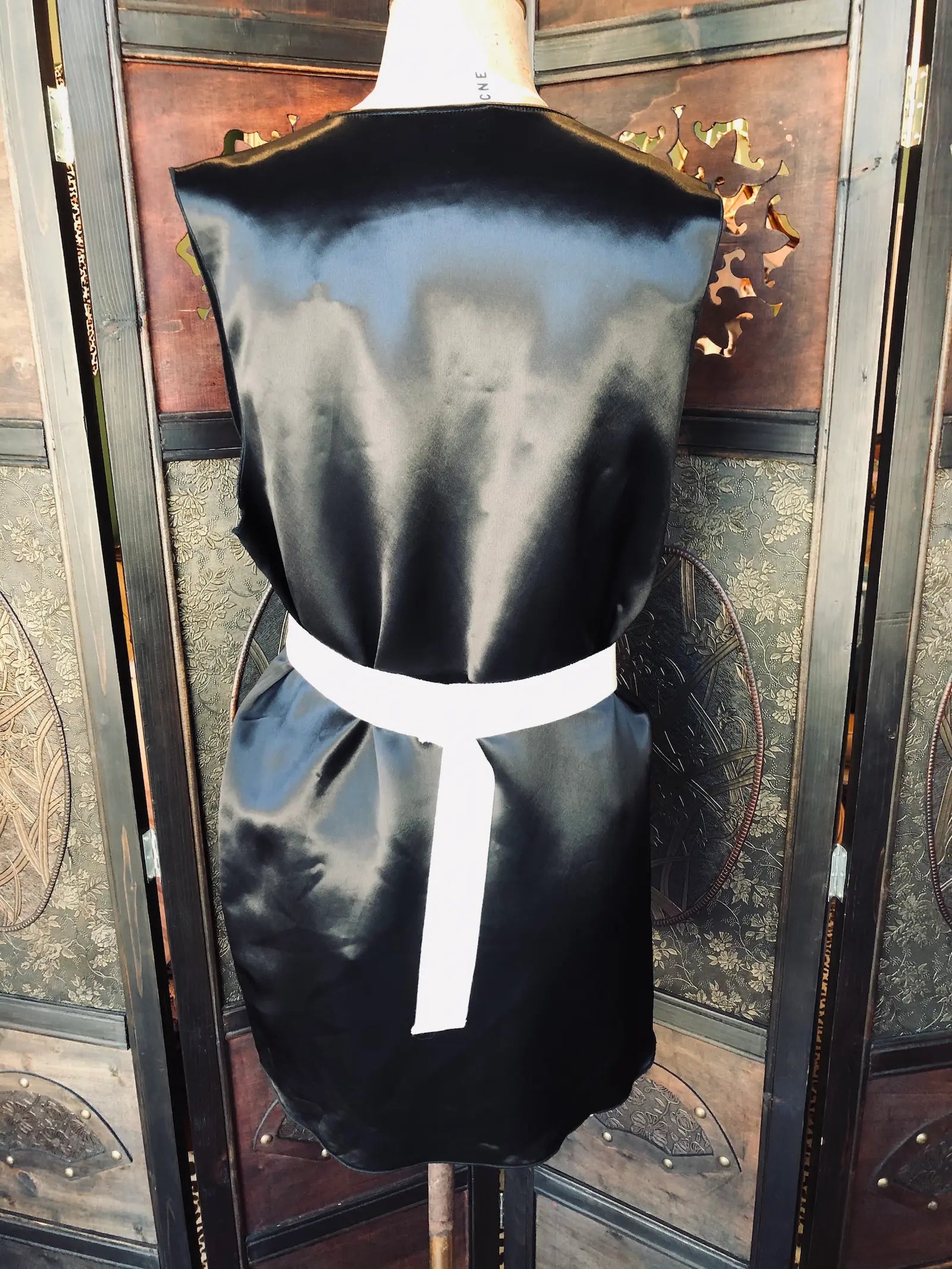 Broochella Acne Studios  black satin dress. Size: 36. Viscose fabric. Black satin finish. V-neckline. Sleeveless design
Straight, relaxed silhouette and soft fluid drape. It is dressed on a vintage mannequin. The background is an ornate, vintage wooden room divider 