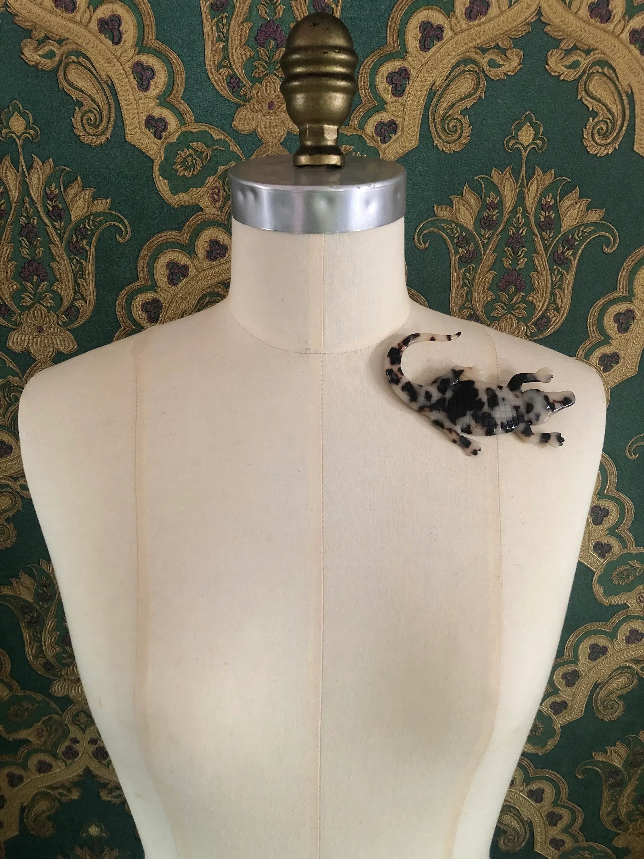 Broochella animalia collection crocodile handmade designer cellulose acetate brooch.  Pictured on a mannequin.  The background is green and gold damask wallpaper