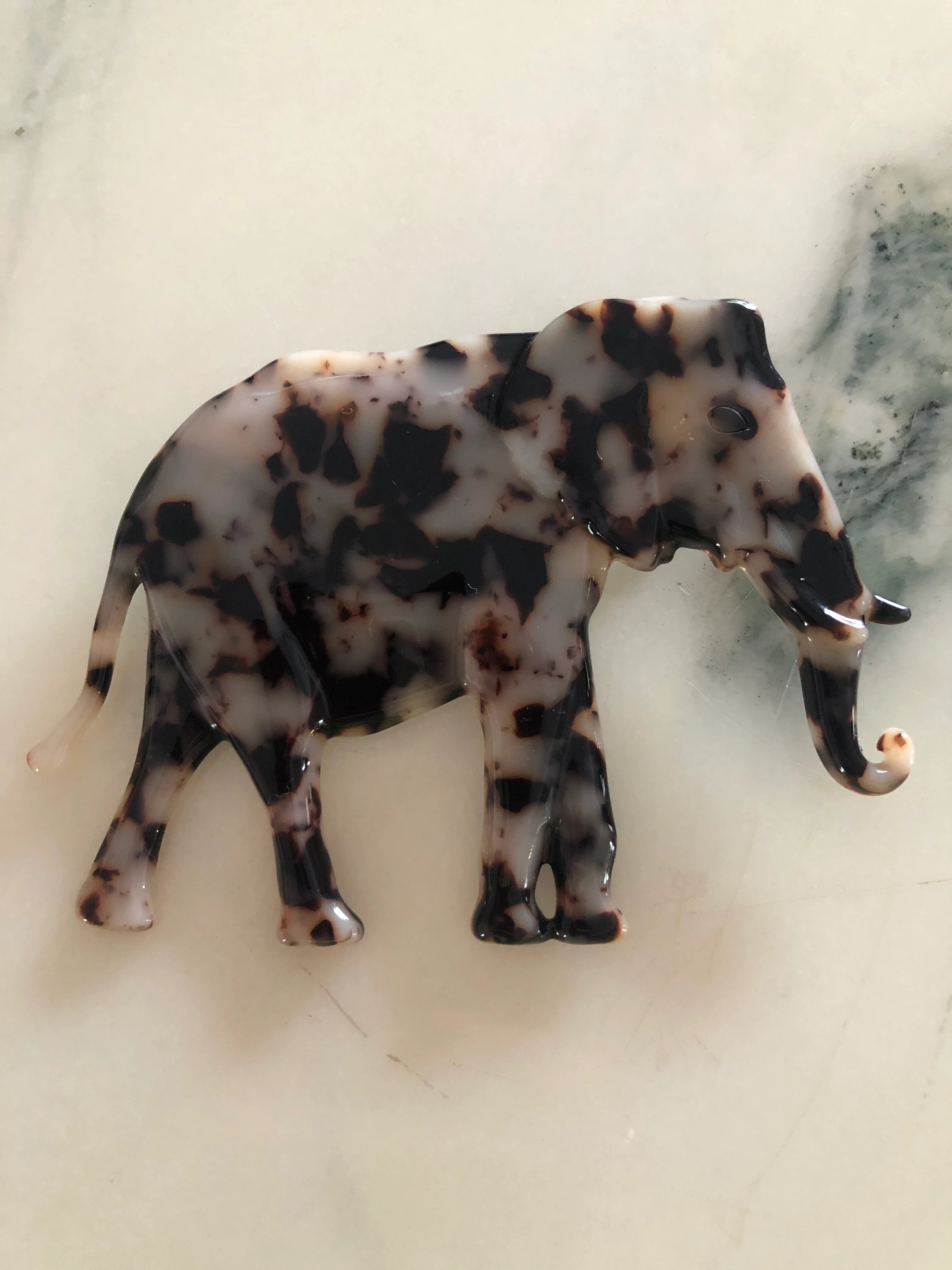 Broochella Animalia brown, figural  hand crafted, cellulose acetate elephant brooch in brown tortoiseshell. The background is white marble