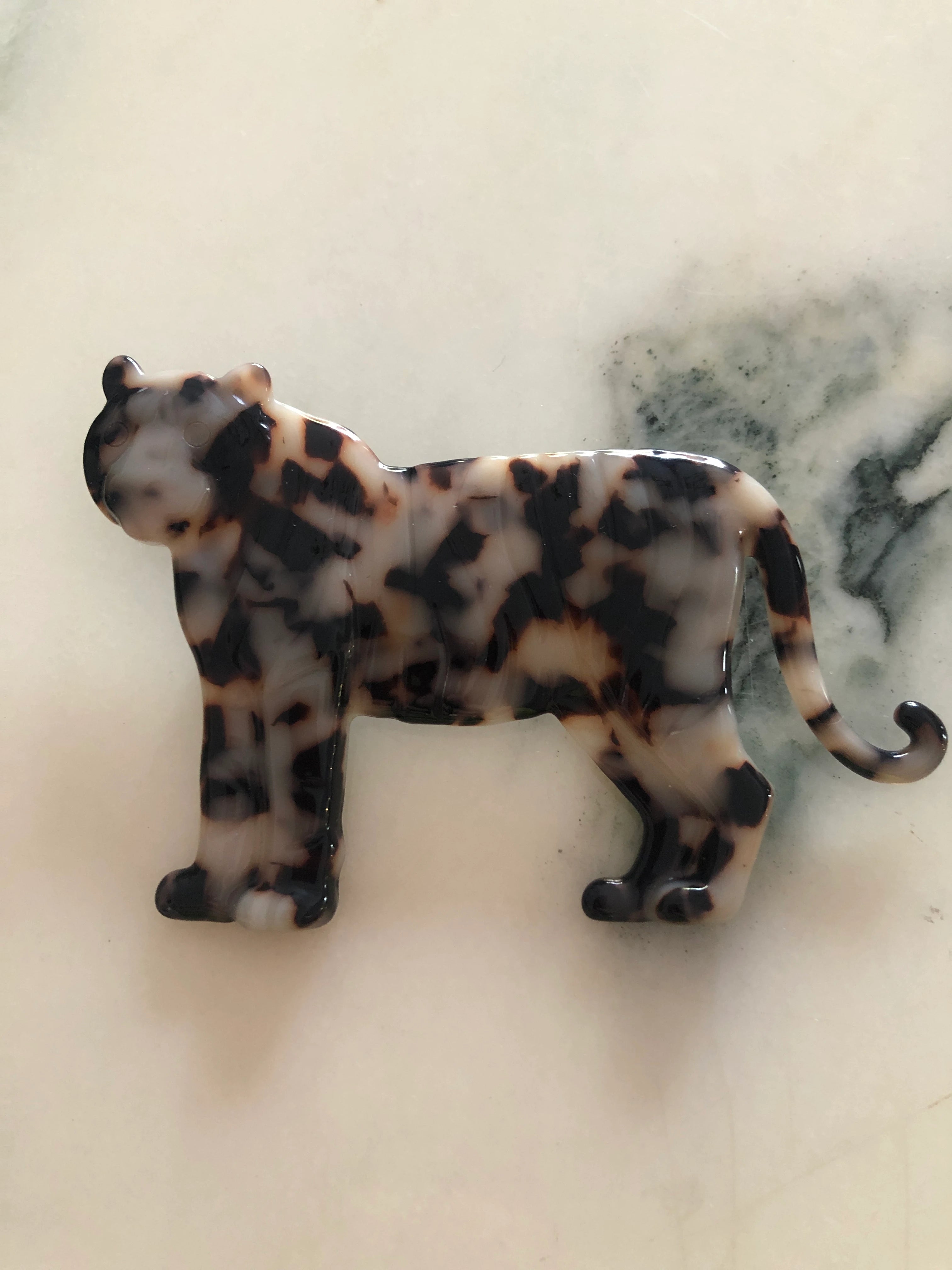 Broochella Animalia handmade tortoiseshell tiger brooch in Italian brown cellulose acetate. The background is white marble