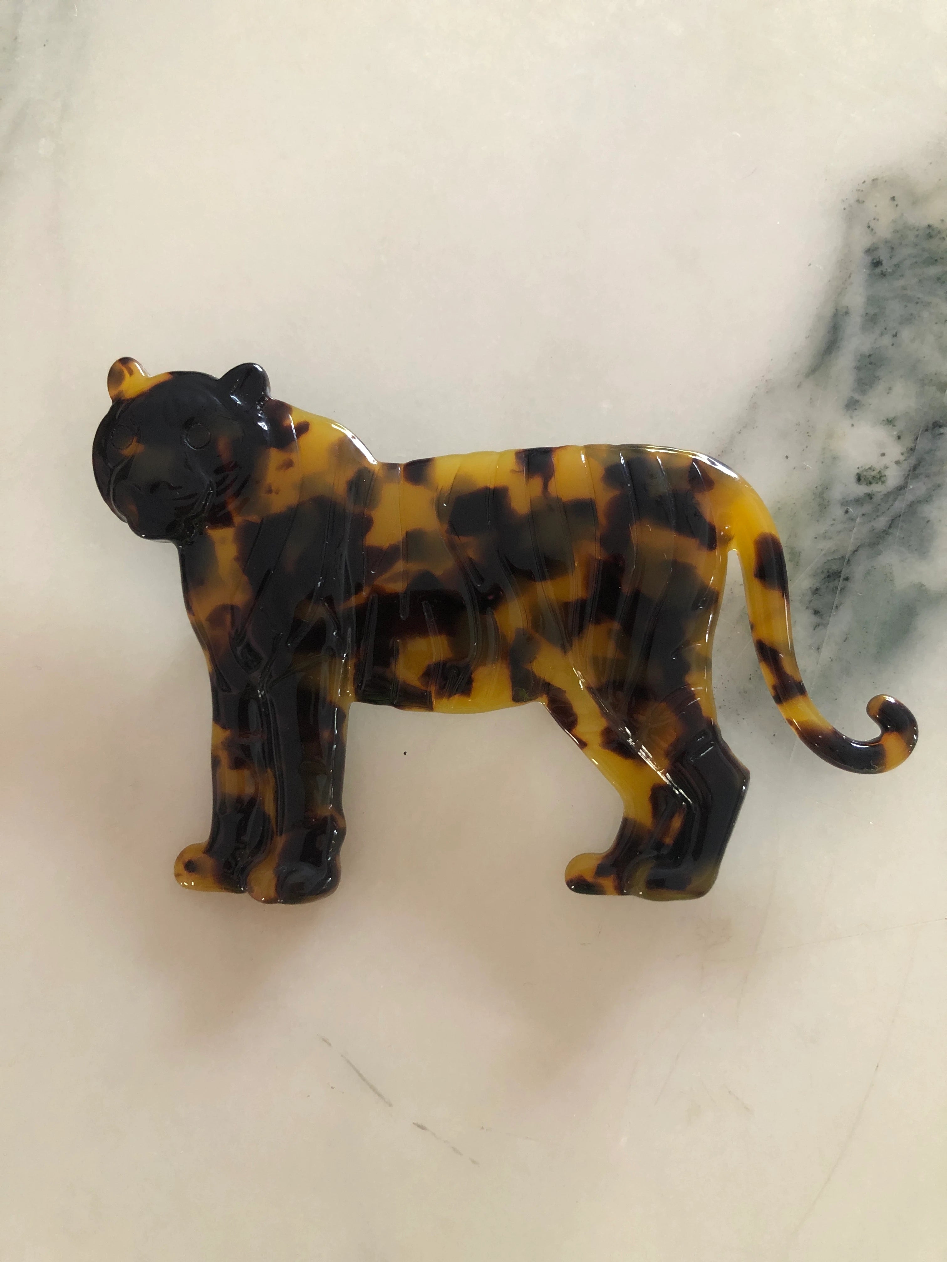 Broochella Animalia handmade tortoiseshell tiger brooch in Italian brown cellulose acetate. The background is white marble