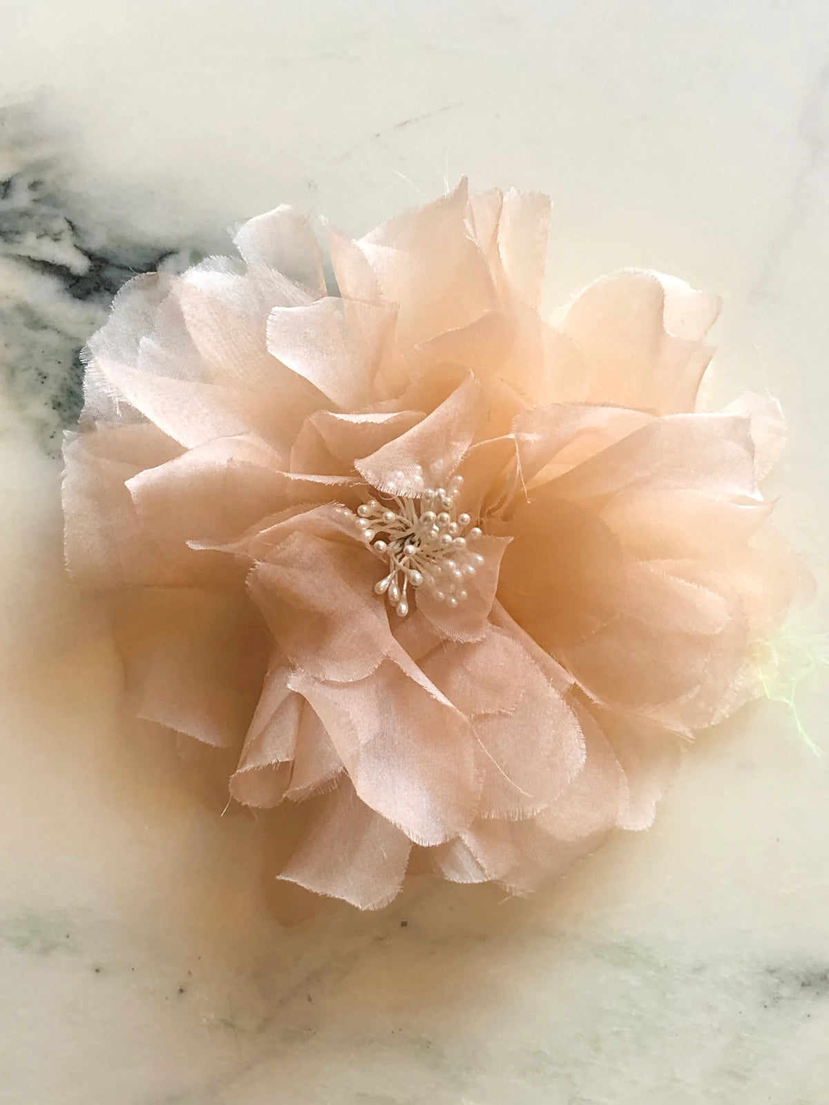 Broochella Aubrieta Flower Brooch Pin in vibrant pink, featuring layered sheer petals and a delicate pearl-effect centre. Pictured on a white marble surface