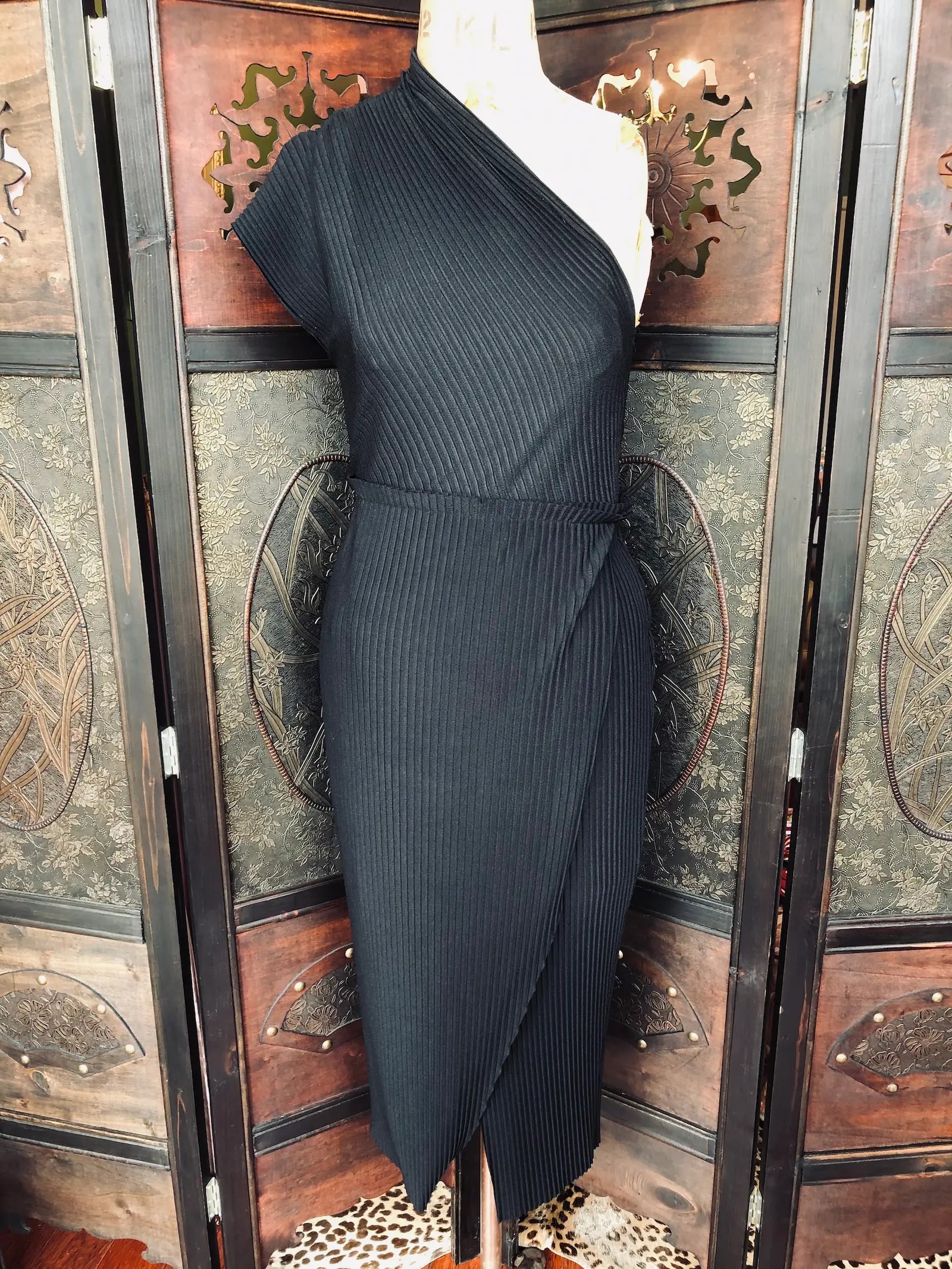 Broochella, The Stylist's Closet Bec and Bridge on shouldered, ribbed, black dress. It is pictured on a vintage mannequin. The background is an ornate, vintage, dark wood room divider. 