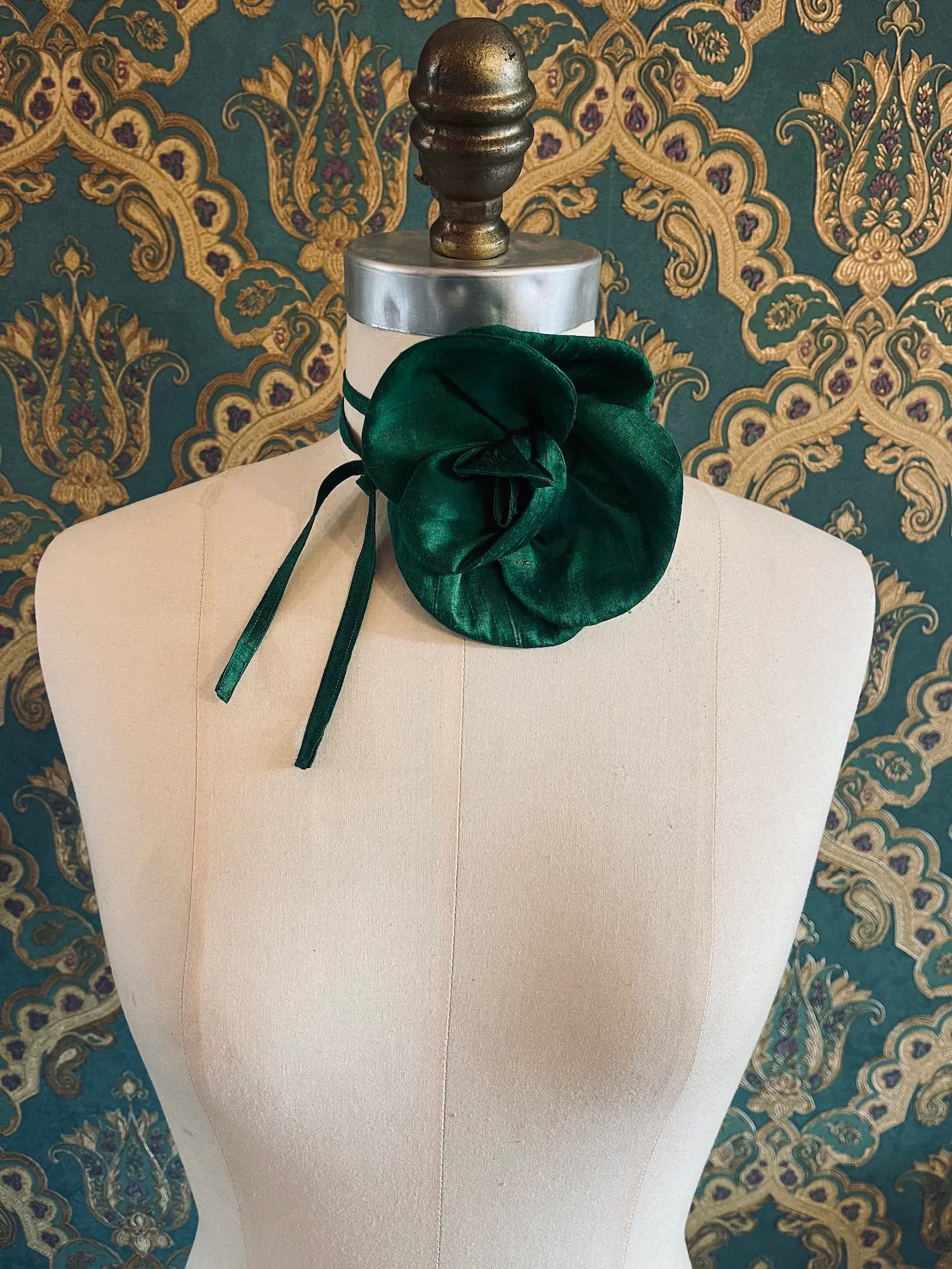 Broochella Bellucci small green handmade silk flower brooch  and choker  Pictured on a mannequin. The background is green and gold damask wallpaper.
