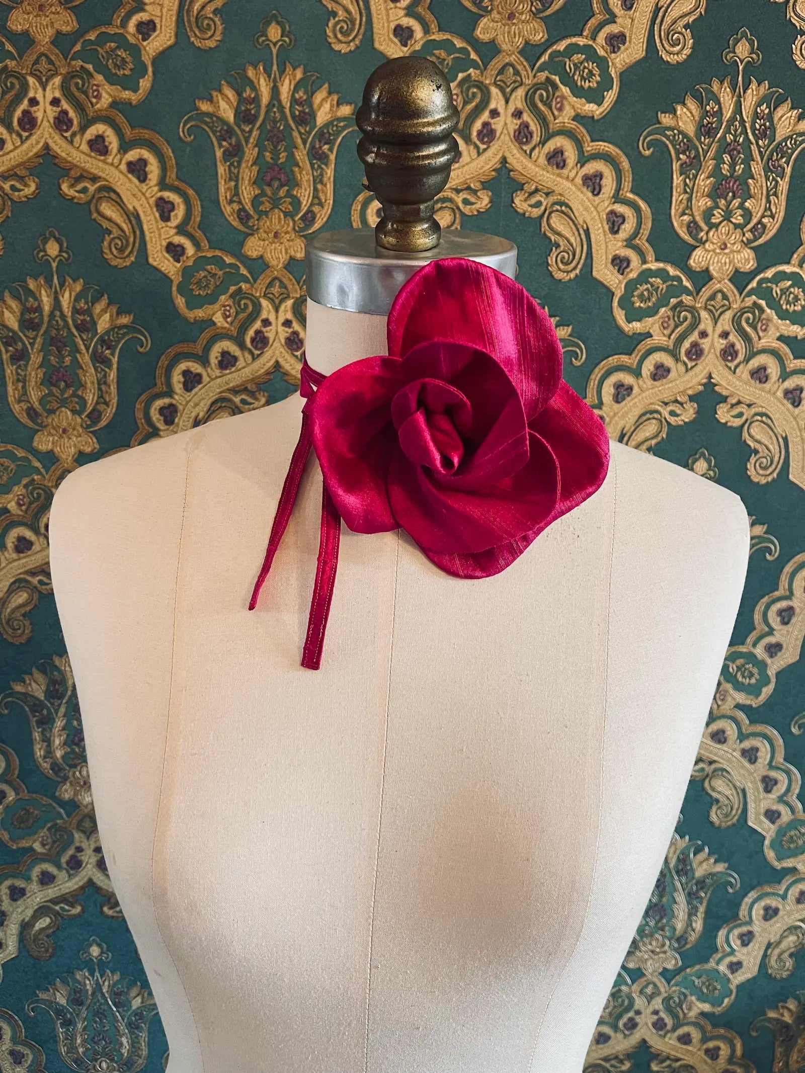Broochella Bellucci small pink handmade silk flower brooch and choker  Pictured on a mannequin. The background is green and gold damask wallpaper.