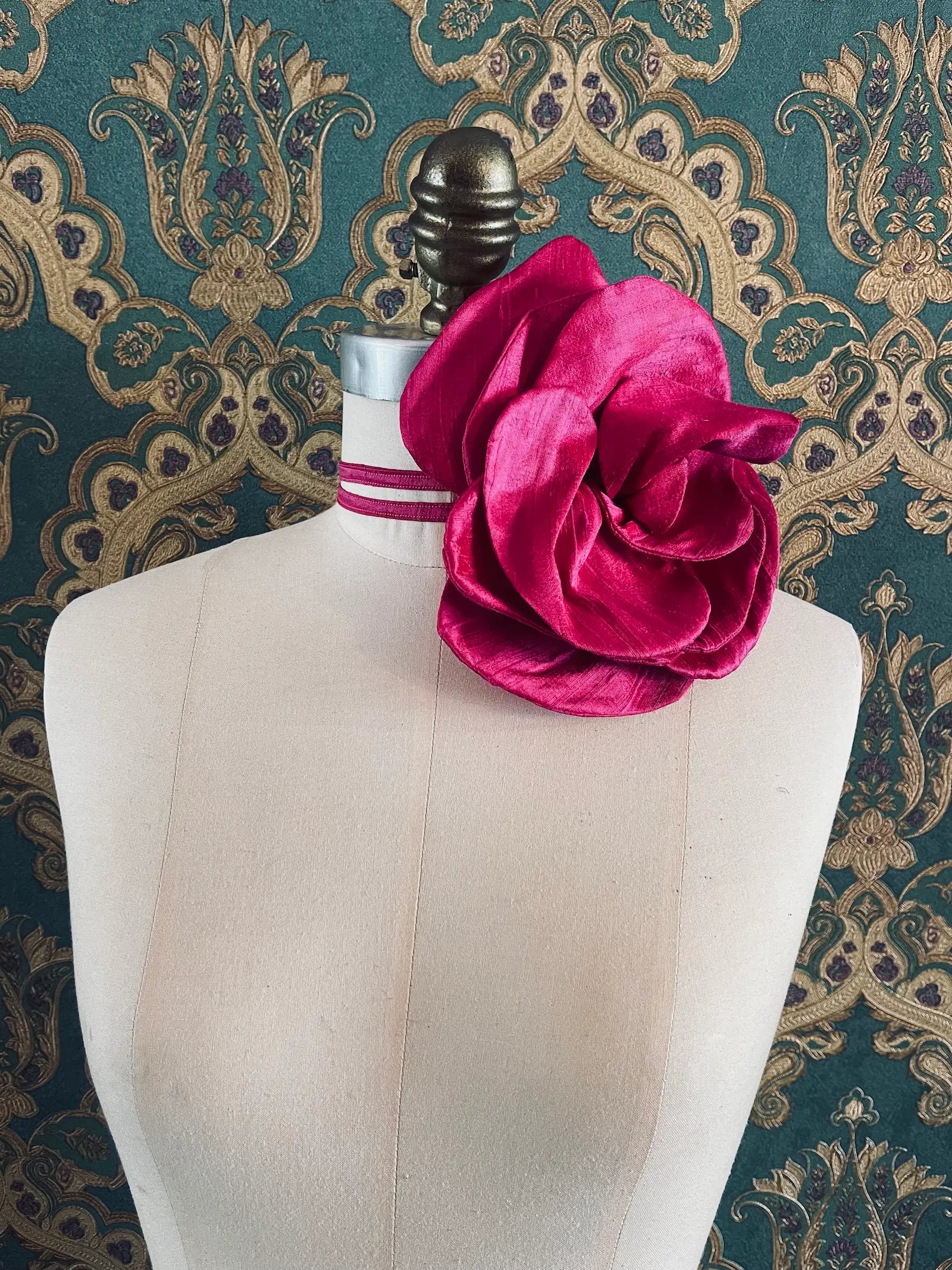 Broochella Bellucci large pink handmade silk flower brooch and choker  Pictured on a mannequin. The background is green and gold damask wallpaper.