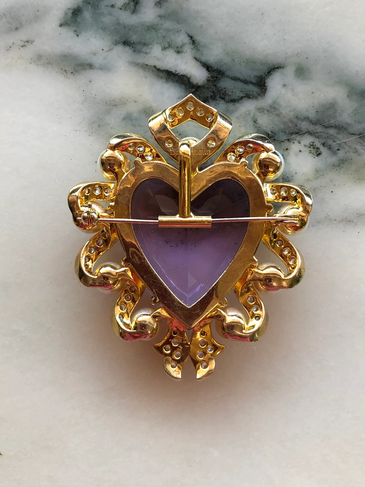 Broochella Brooch-to-Necklace Converter Horizontal in polished gold, photographed in use on the back of the Giulietta e Romeo Brooch Pin on a white and grey marble background.