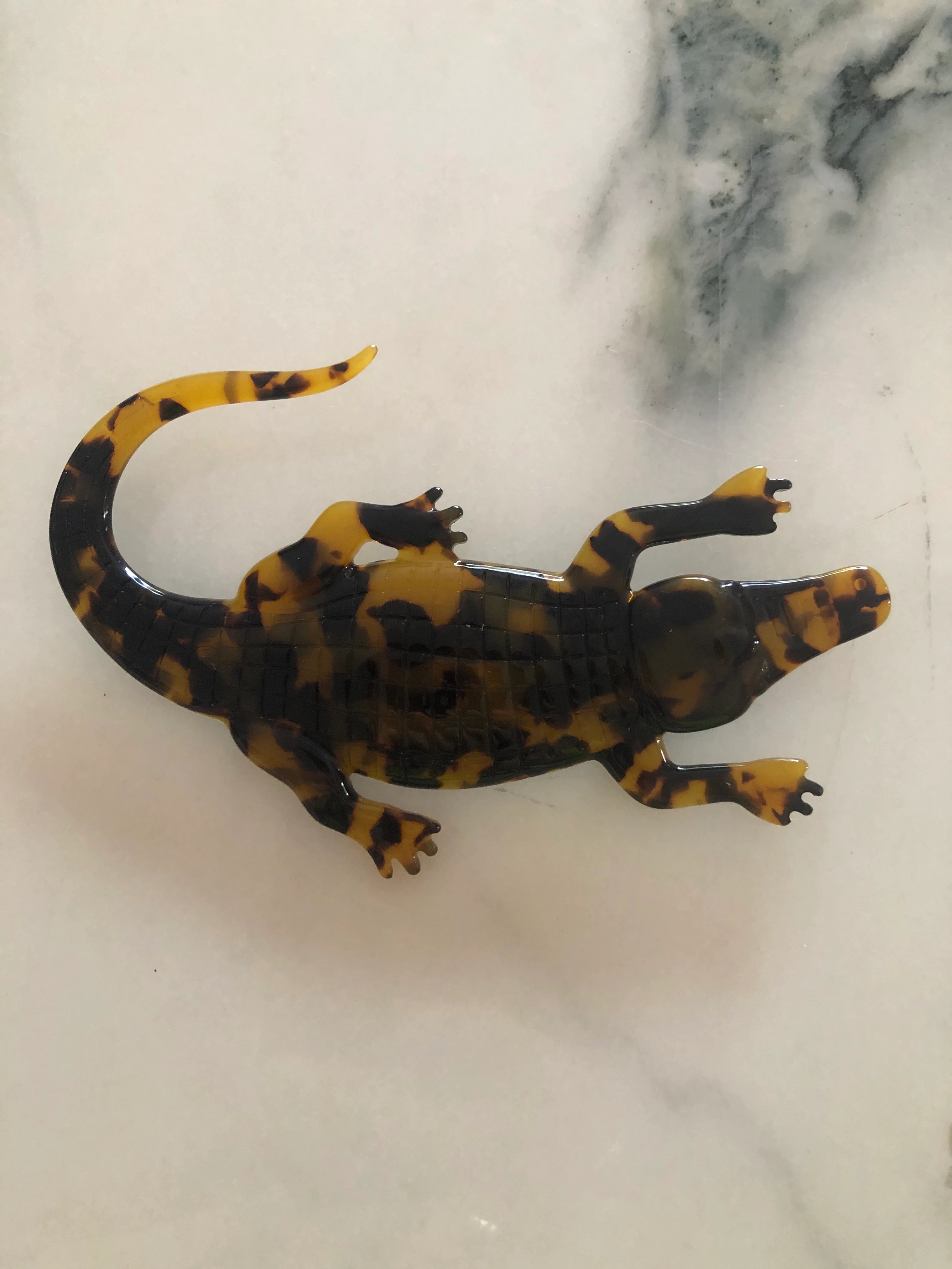 Broochella Men's beige Animalia tortoiseshell giraffe shaped brooch. It is made from Premium Italian cellulose tortoiseshell acetate. It is presented on a white marble surface.