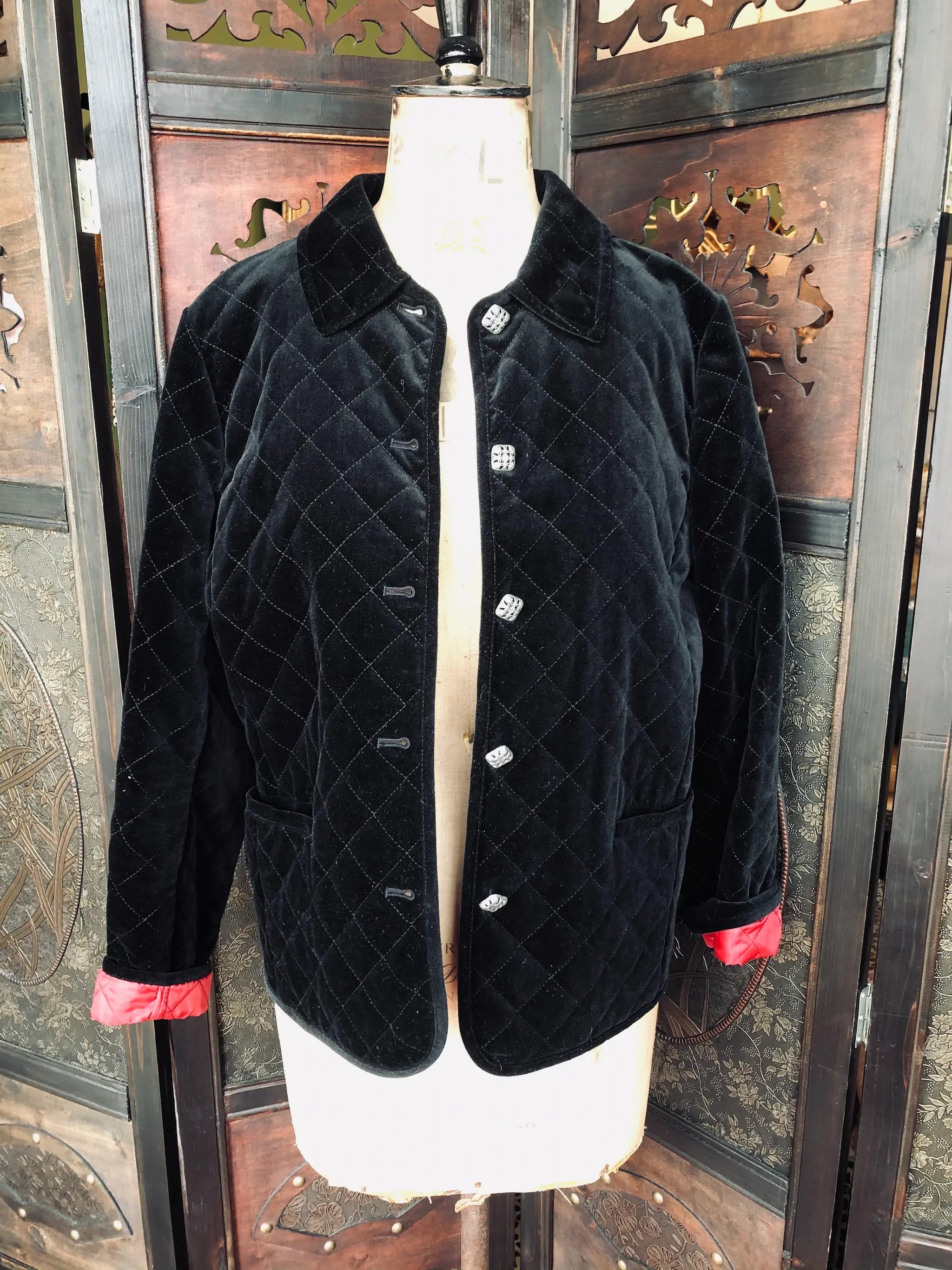 Broochella Charter Club size medium Black quilted velvet jacket with red trim on a mannequin against a decorative wooden background