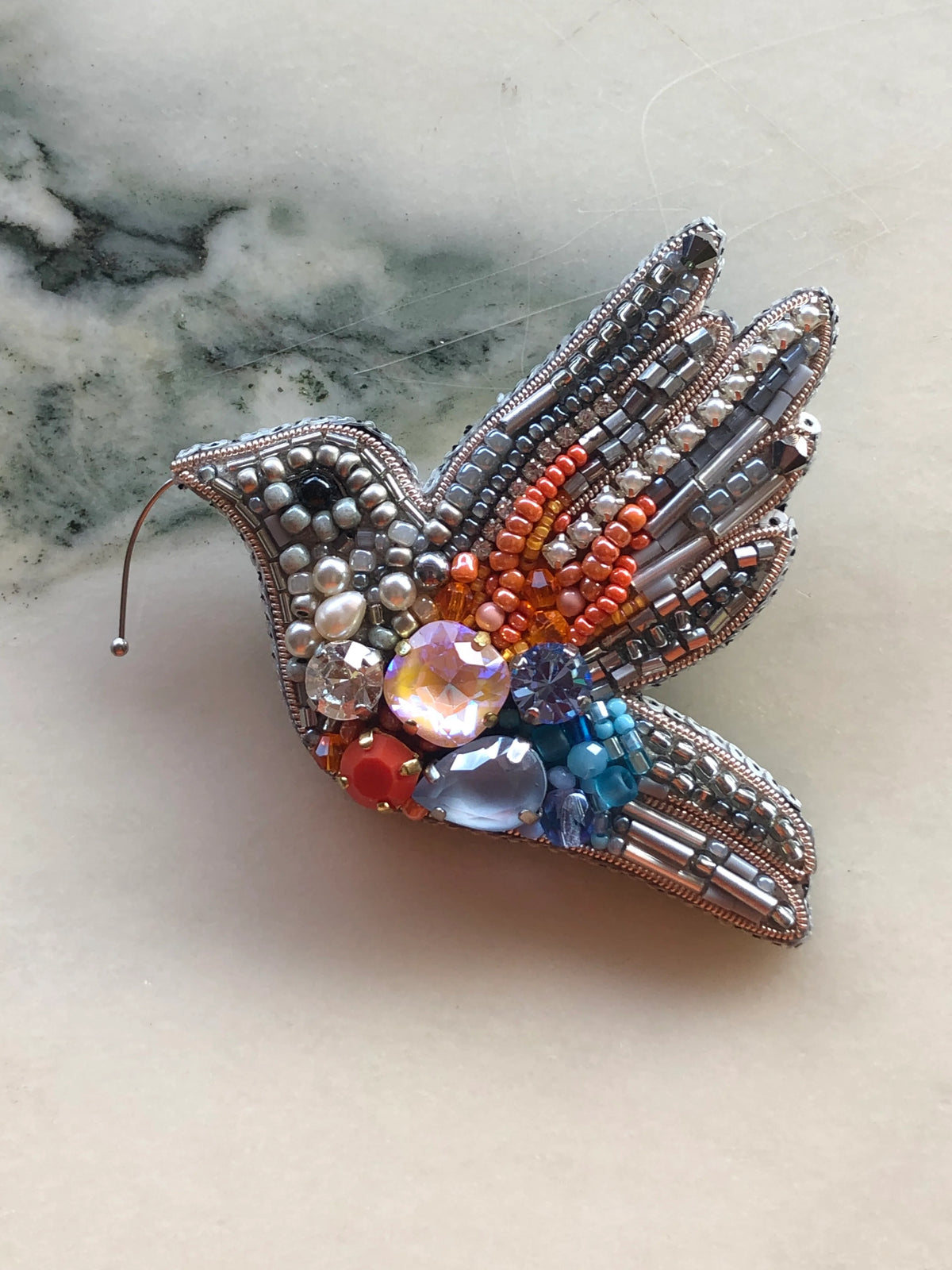 Broochella Colomba Dove Brooch, hand-beaded with silver, coral, blue and metallic beads, pearls and faceted crystals in a flying dove design.