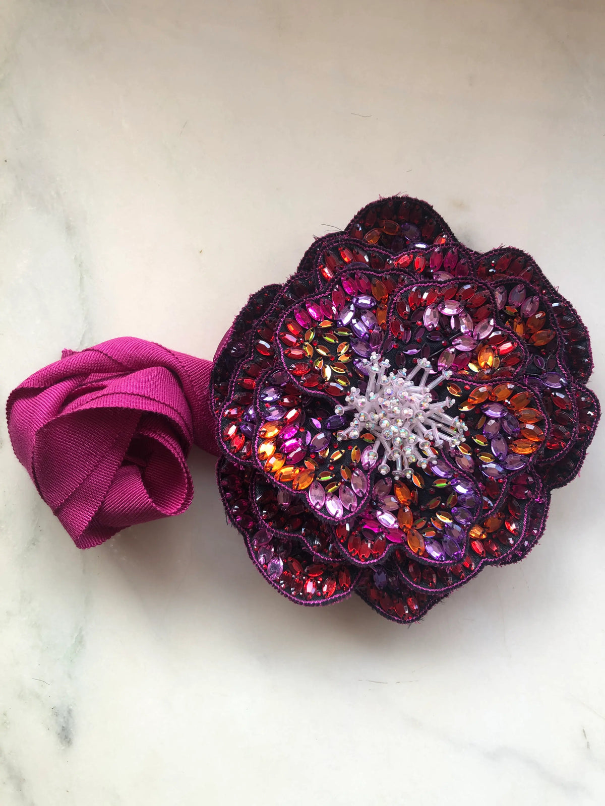 Broochella Cristallino large hand-beaded flower choker and brooch in fuchsia, purple, red and orange crystals with matching ribbon, photographed on white marble.