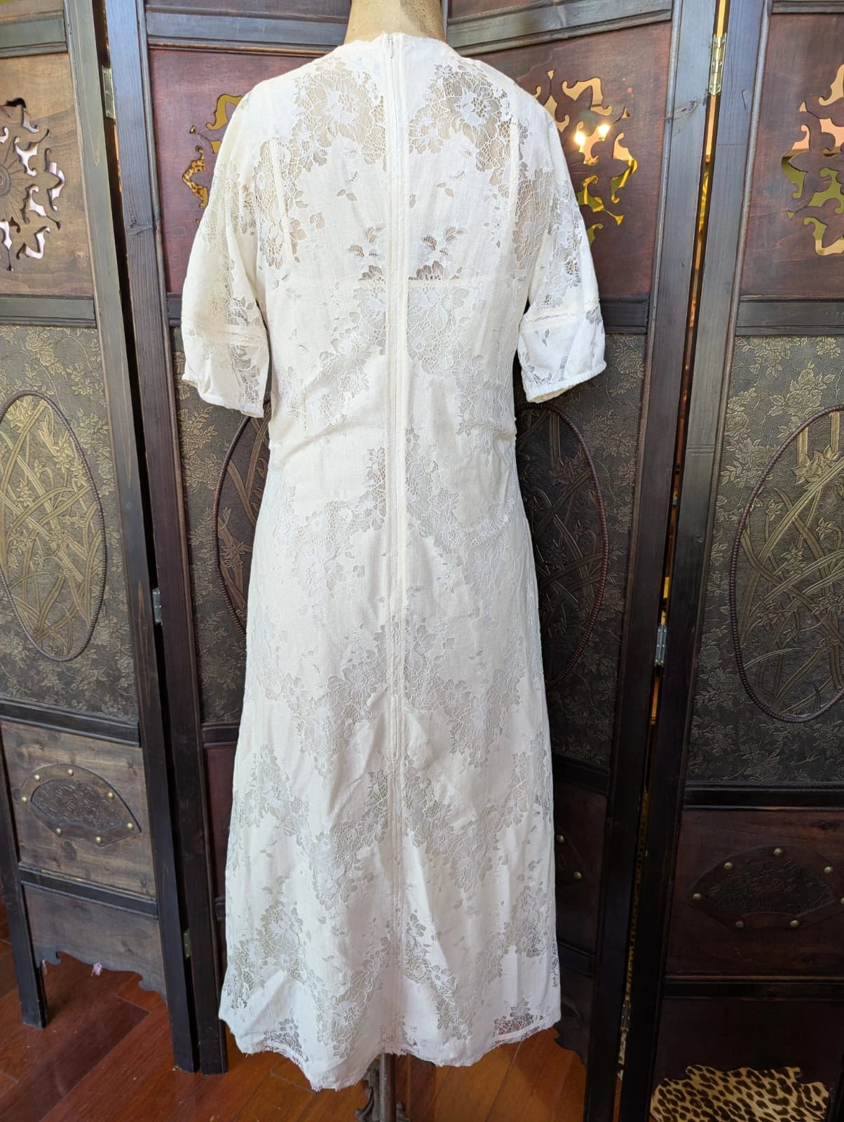 Broochella Day by Birger et Mikkelsen designer  back view of a White lace midi dress on a mannequin against an ornate wooden background