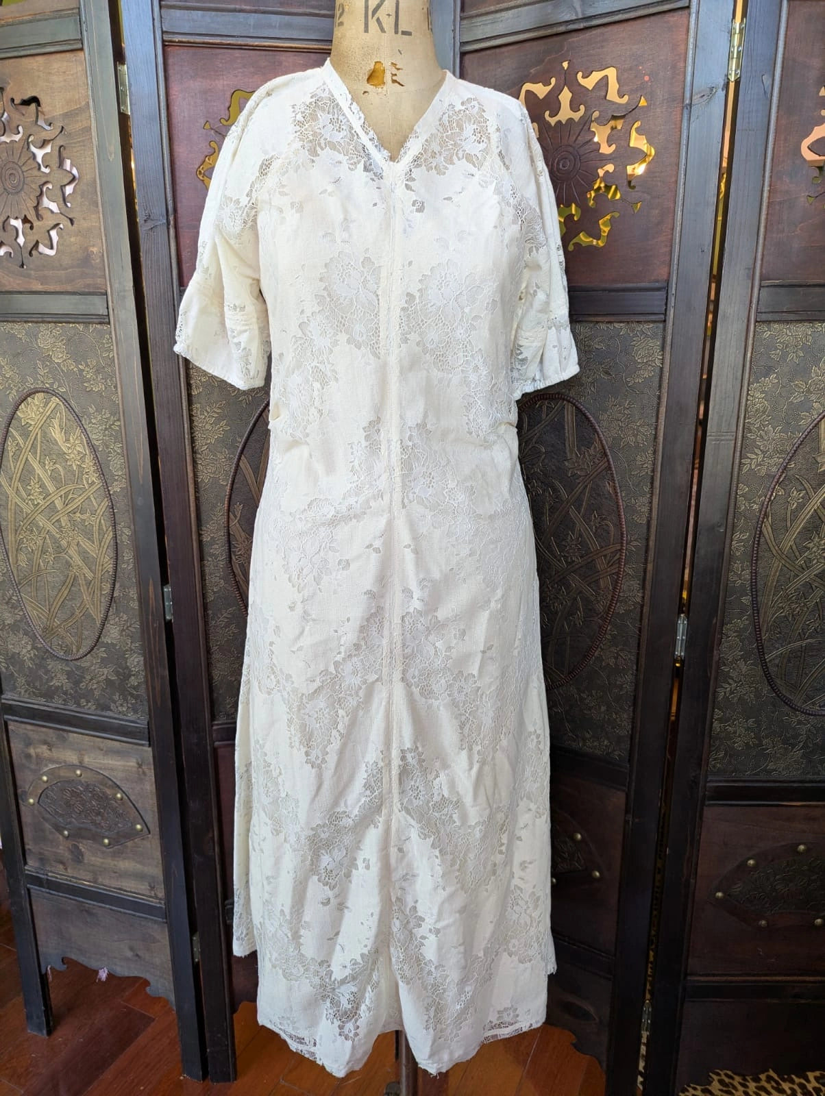 Broochella Day by Birger et Mikkelsen designer  White lace midi dress on a mannequin against an ornate wooden background