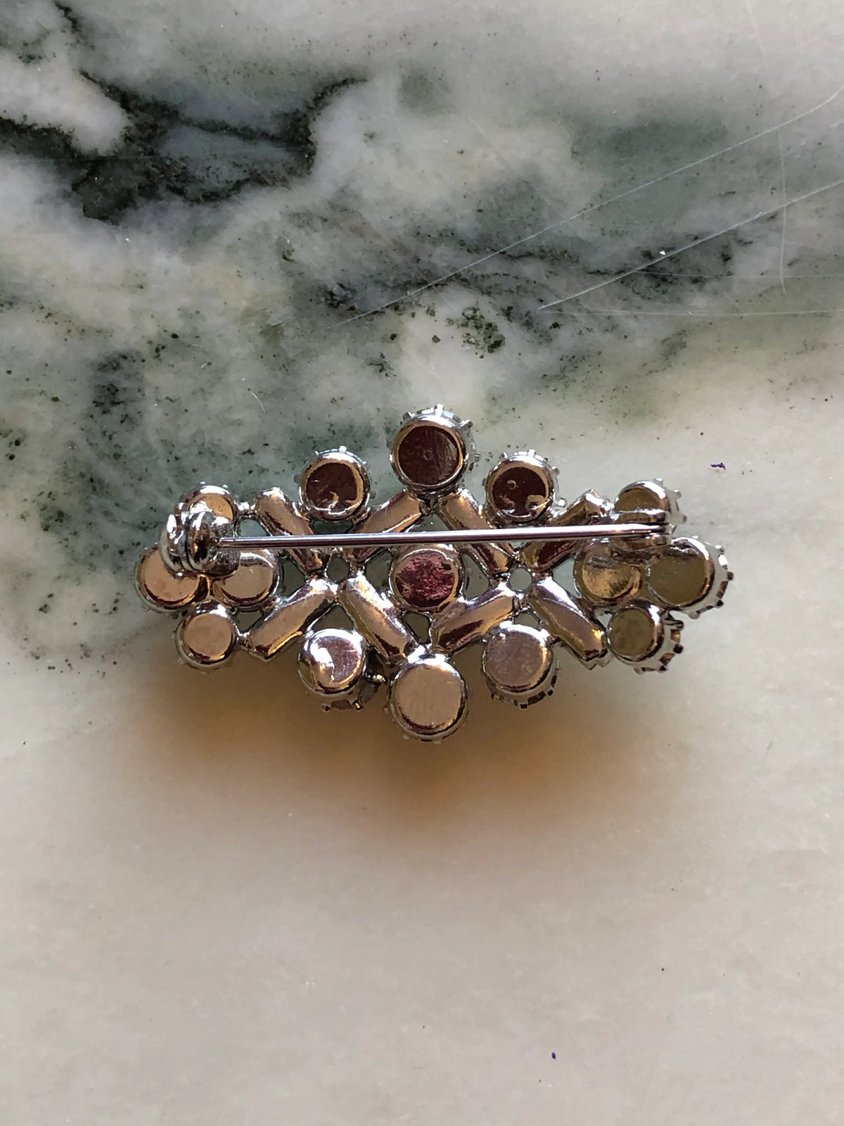 Broochella Donatella Vintage Crystal Lattice Brooch featuring round and baguette-cut clear crystals in an open geometric silver-tone setting on a cream and grey marble background.