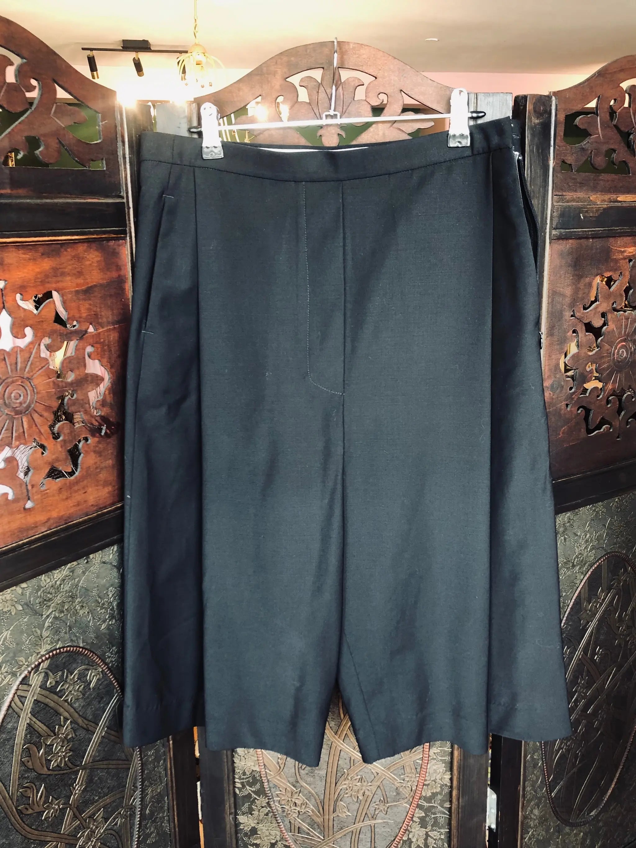 Broochella The Stylist's Closet Ellery black tailored wool shorts. They are hanging from an ornate wooden room divider