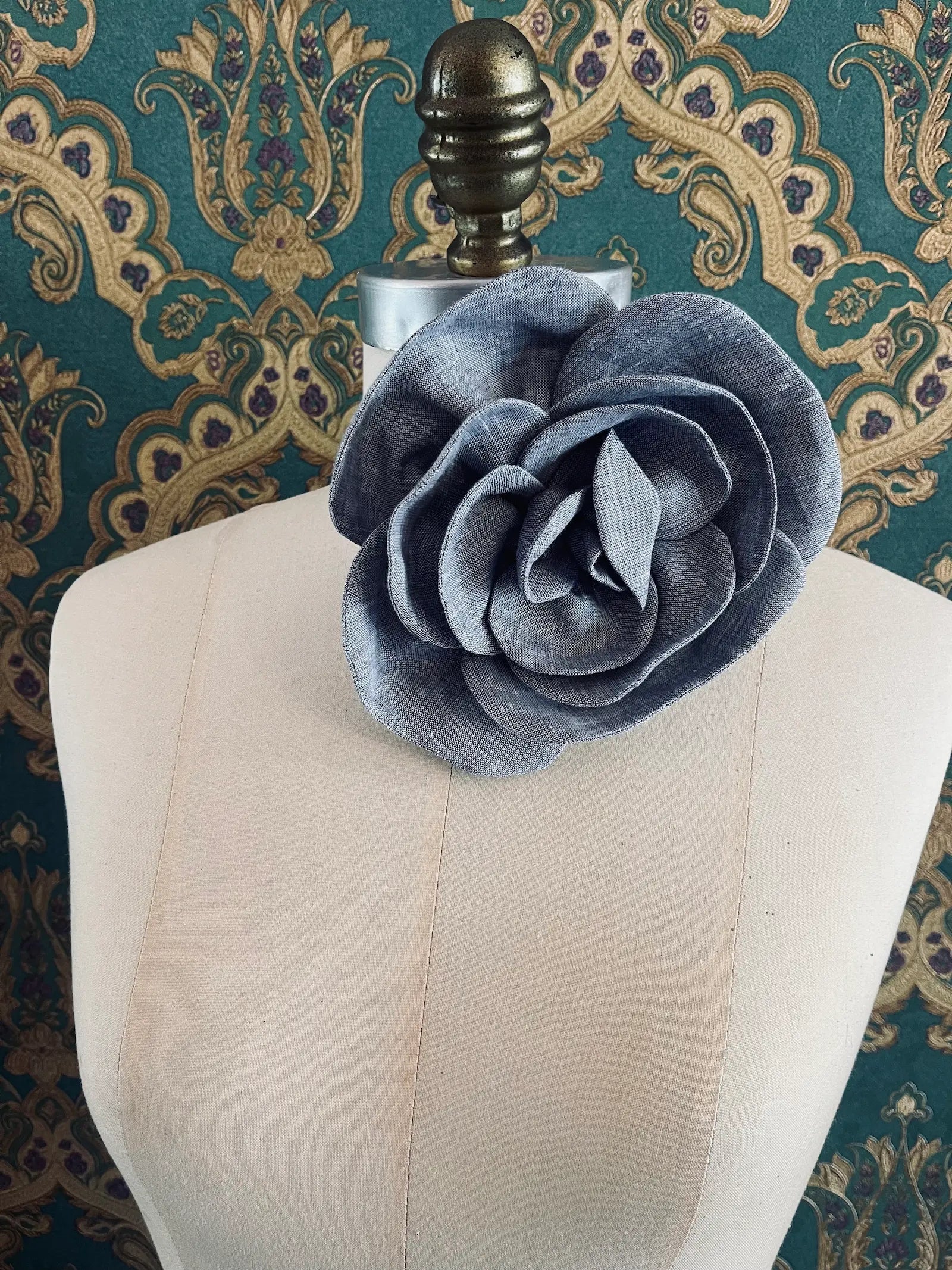 Broochella Florella large grey handmade linen flower brooch and choker  Pictured on a mannequin. The background is green and gold damask wallpaper.