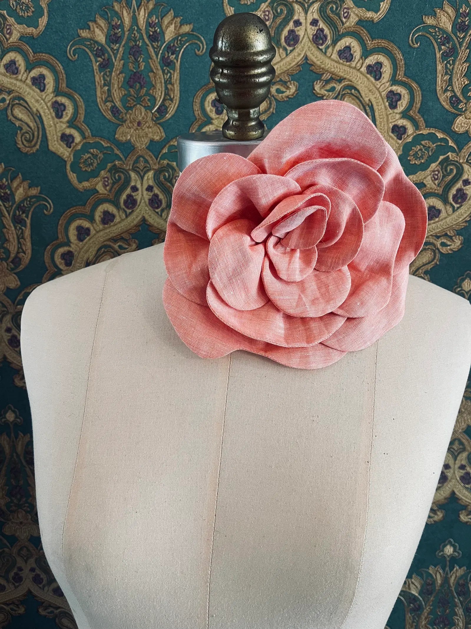 Broochella Florella large orange handmade linen flower brooch and choker  Pictured on a mannequin. The background is green and gold damask wallpaper.