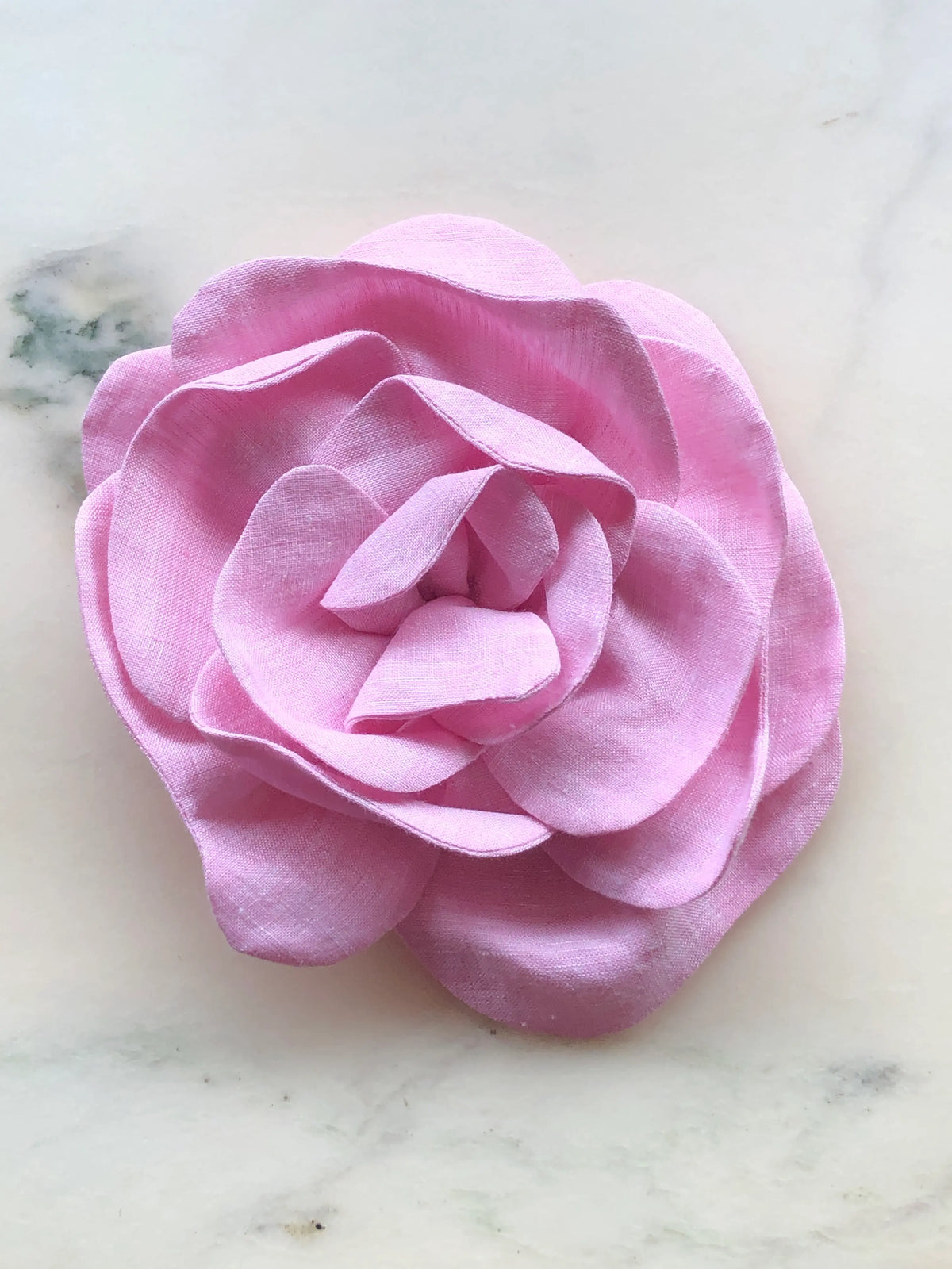 Large pink Broochella Florella Linen Flower Brooch with sculptural layered linen petals, photographed on a white marble background with soft grey veining.