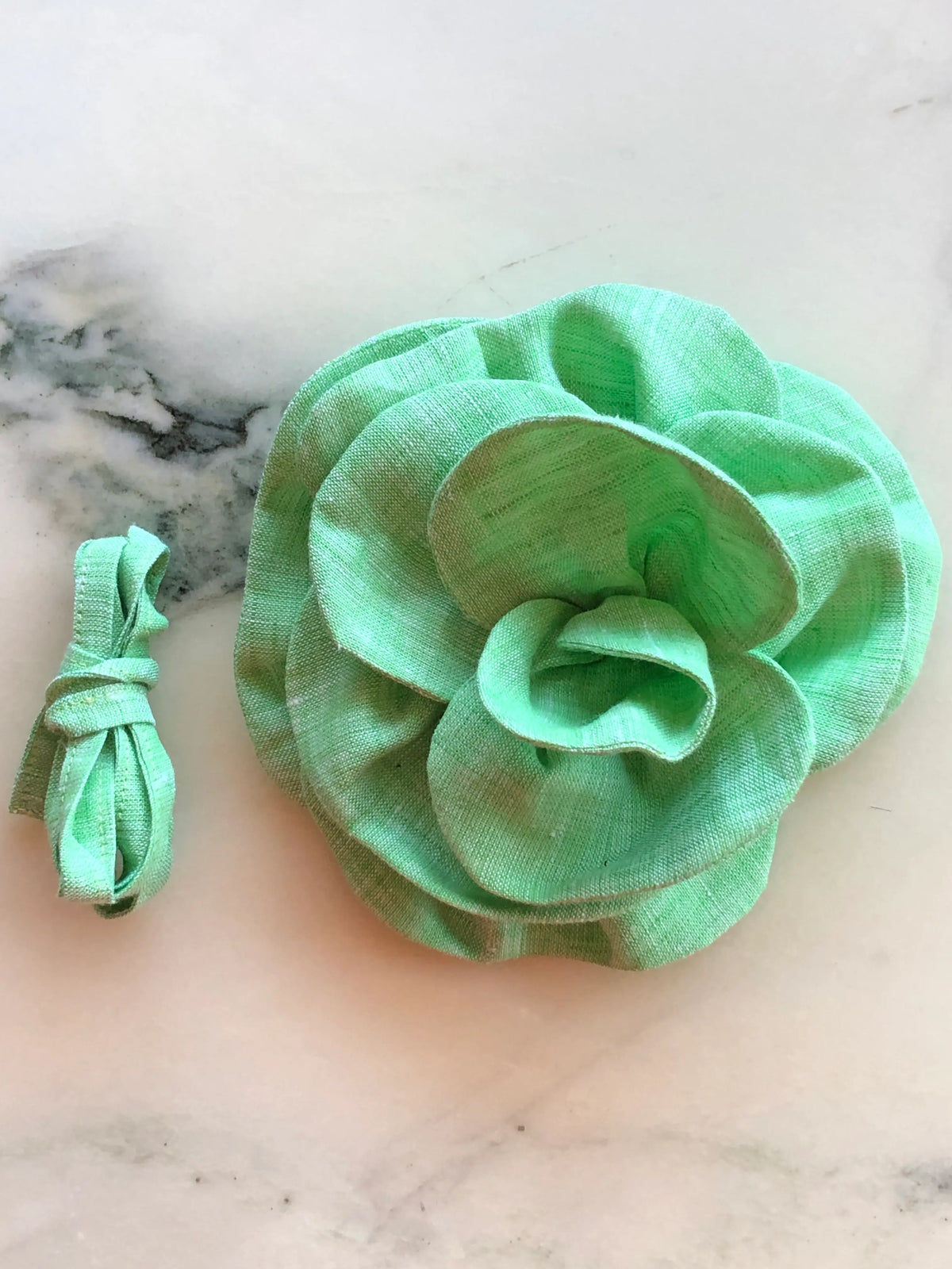 Broochella Florella small green linen flower choker and brooch with matching ribbon, photographed on a white marble background.