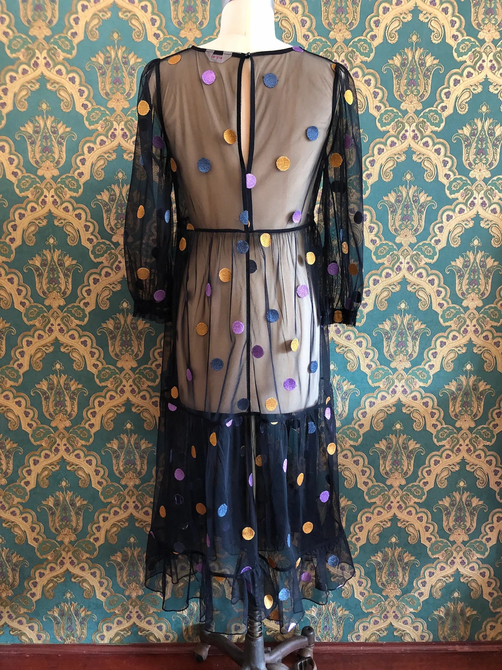Broochella Gorman black mesh maxi dress with multicoloured metallic polka dots, long sleeves and a flowing layered hem, size AU 8. Pictured on a mannequin against green and gold damask wallpaper.