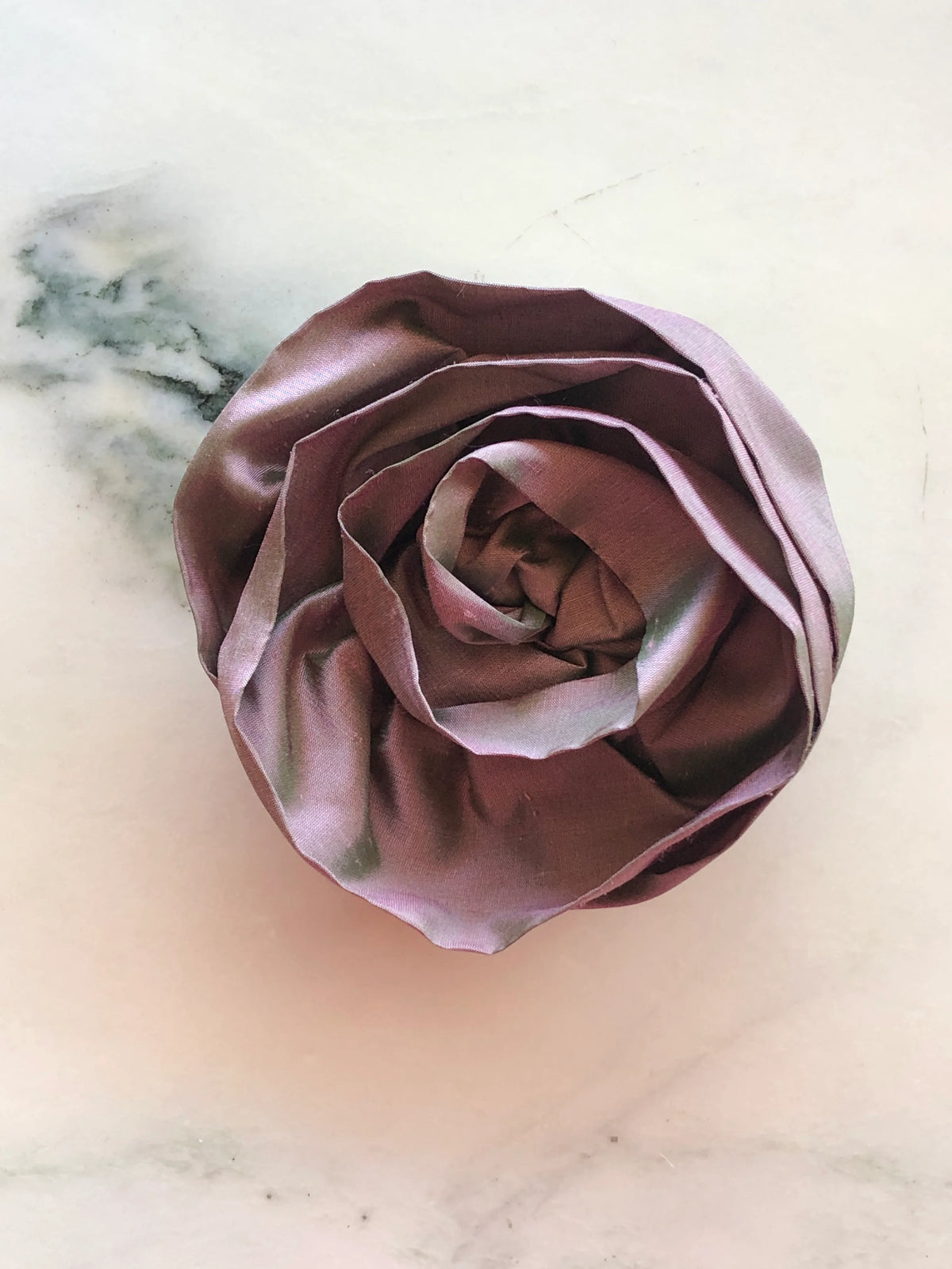 Handmade Broochella Isabella Rossellini designer silk flower brooch in purple, featuring dramatic layered rosette petals and a softly structured finish, photographed on white marble.