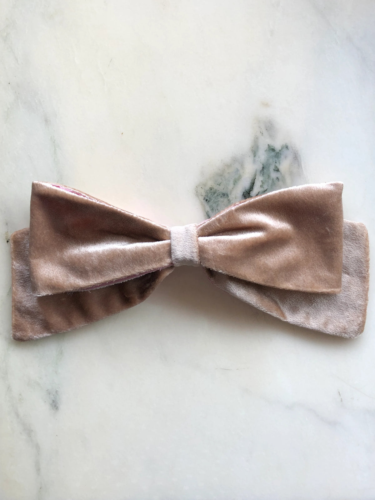 Broochella handmade Large Velvet Bow Brooch in luxurious champagne velvet with contrasting pink lining, featuring an oversized designer double bow with sculptural loops, photographed on white marble.