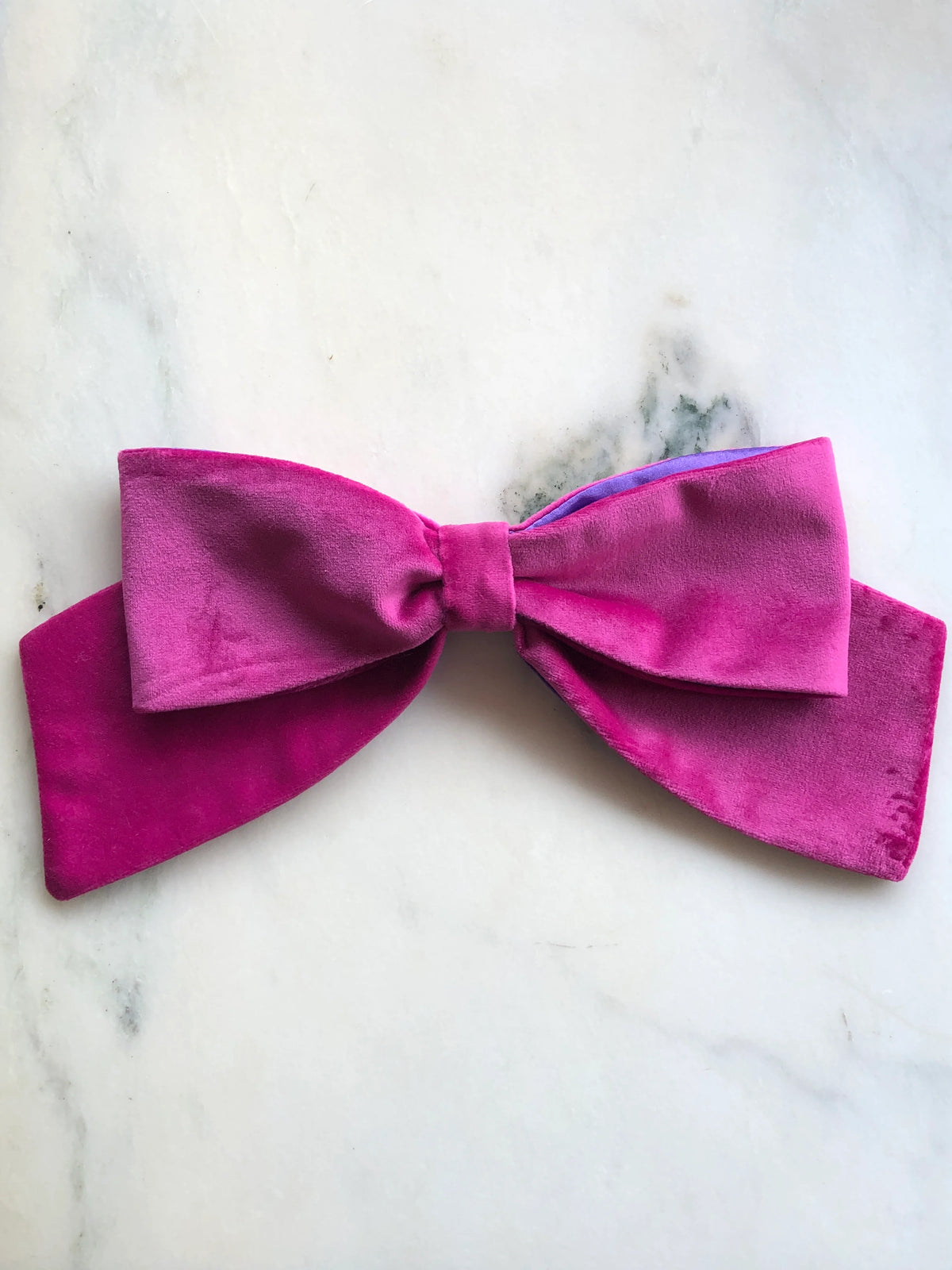 Broochella handmade Large Velvet Bow Brooch in rich magenta velvet with contrasting purple edging, featuring an oversized designer double bow with sculptural loops, photographed on white marble.