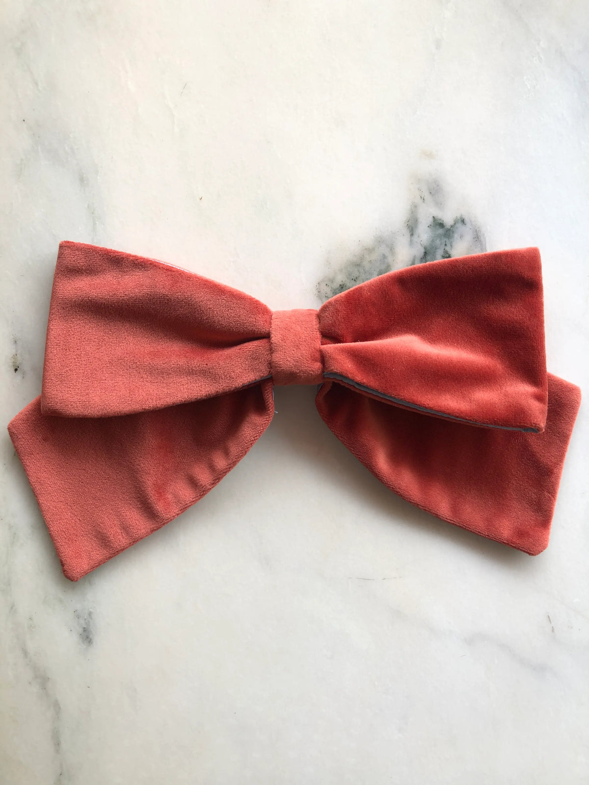 Broochella handmade Large Velvet Bow Brooch in rich burnt orange velvet with contrasting ice blue edging, featuring an oversized designer double bow with sculptural loops, photographed on white marble.