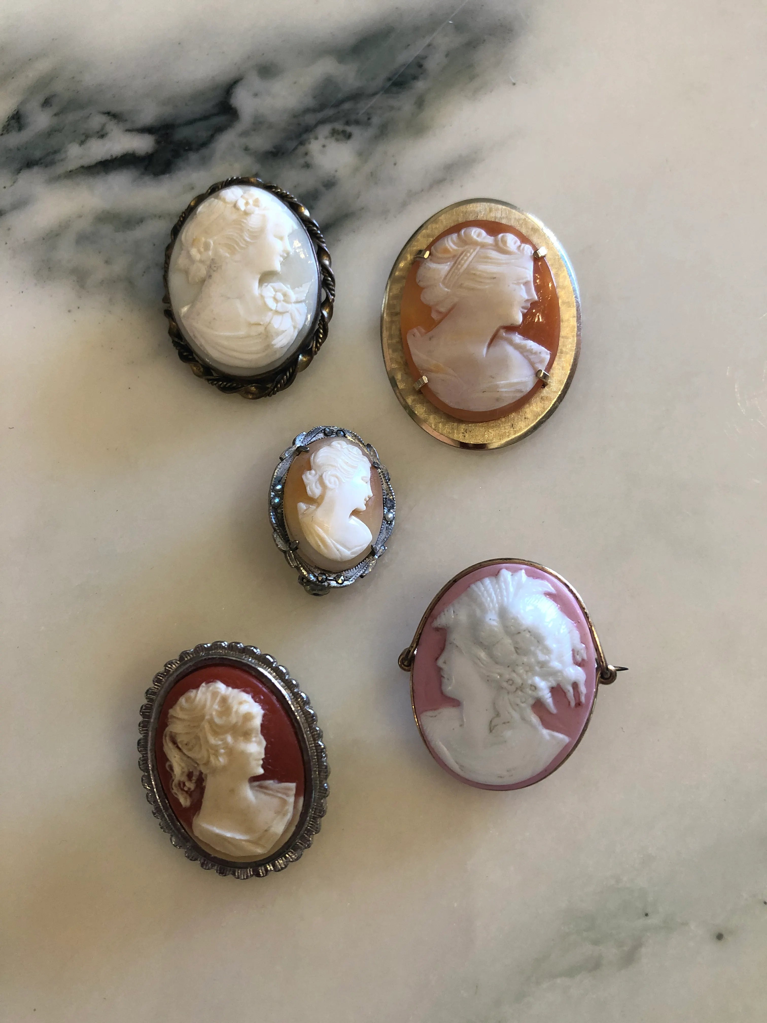 Broochella le camee set of five vintage cameo brooches. The background is white marble