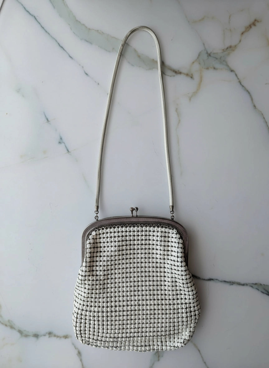 Broochella Maison Broche le bijou du soir vintage white glomesh bag, with vintage brooch embellishments. The background is white marble.