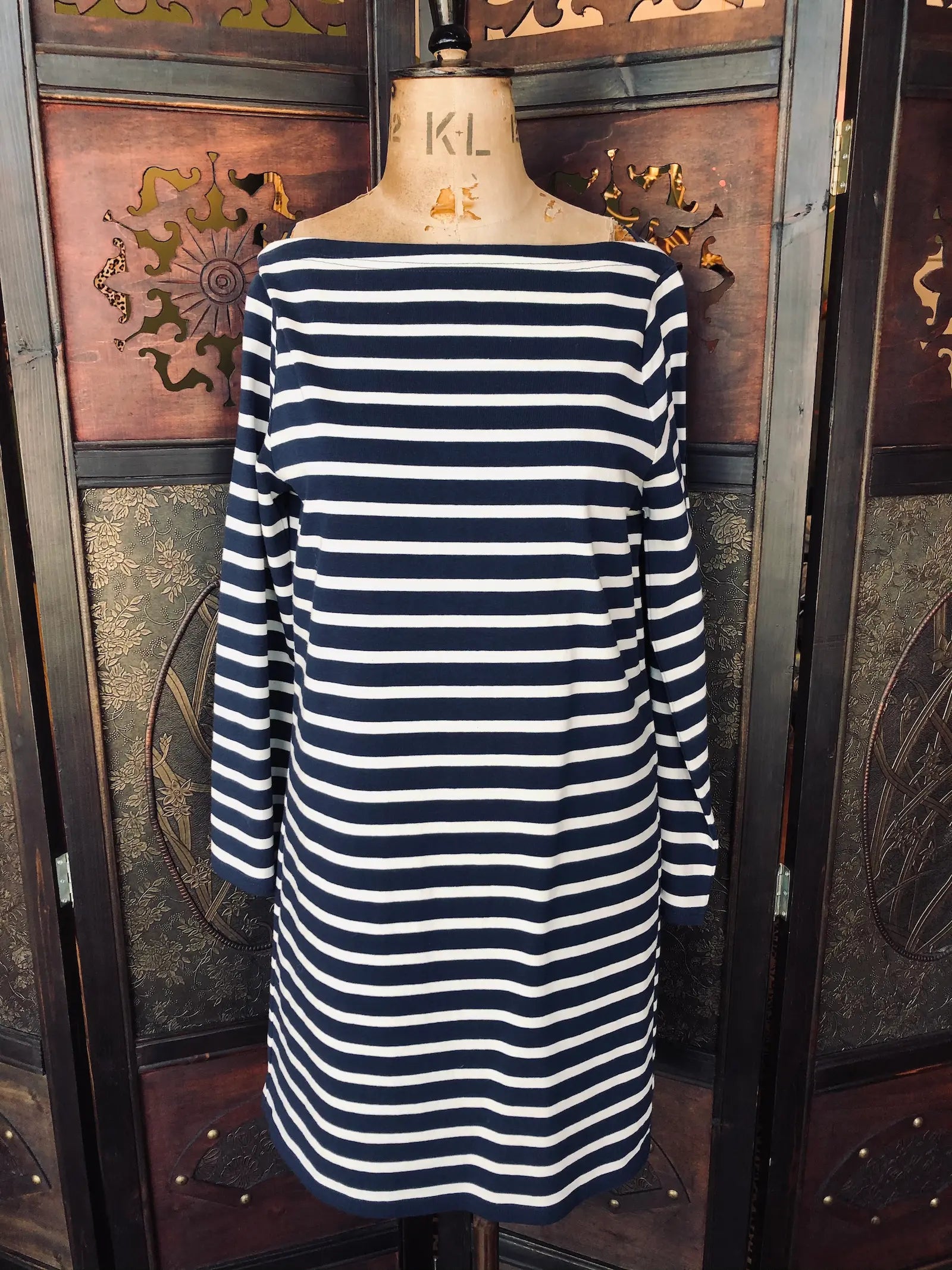 Broochella Marc Jacobs dress size small. It is navy and ivory stripe, 100% Cotton, bateau neckline, long sleeves, knee-length and straight fit. It is pictured on a mannequin. The background is an ornate, dark wood, vintage room divider. 
