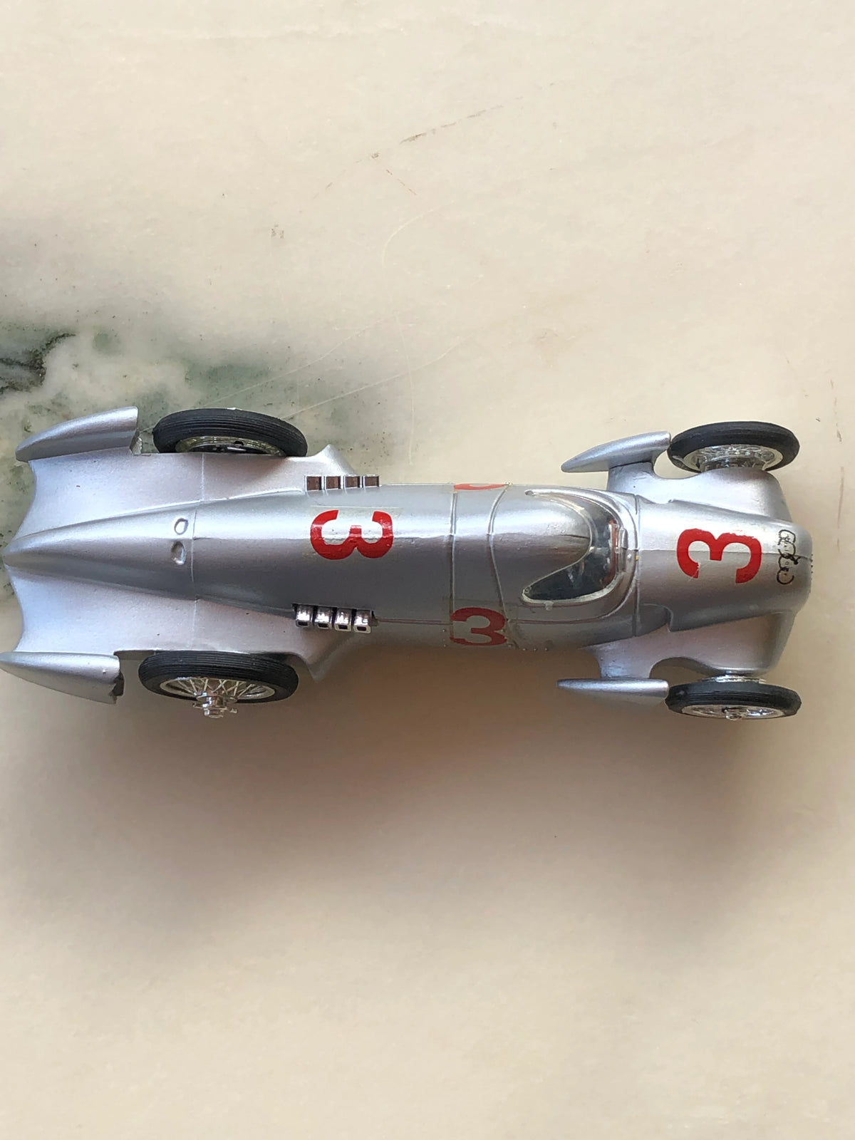 Broochella Men's Argento No.3 Vintage Formula One Racing Car Brooch in side profile, featuring a sleek silver body, red number 3 decal, chrome wire-spoke wheels, side exhaust detailing and visible metal brooch pin fastening.
