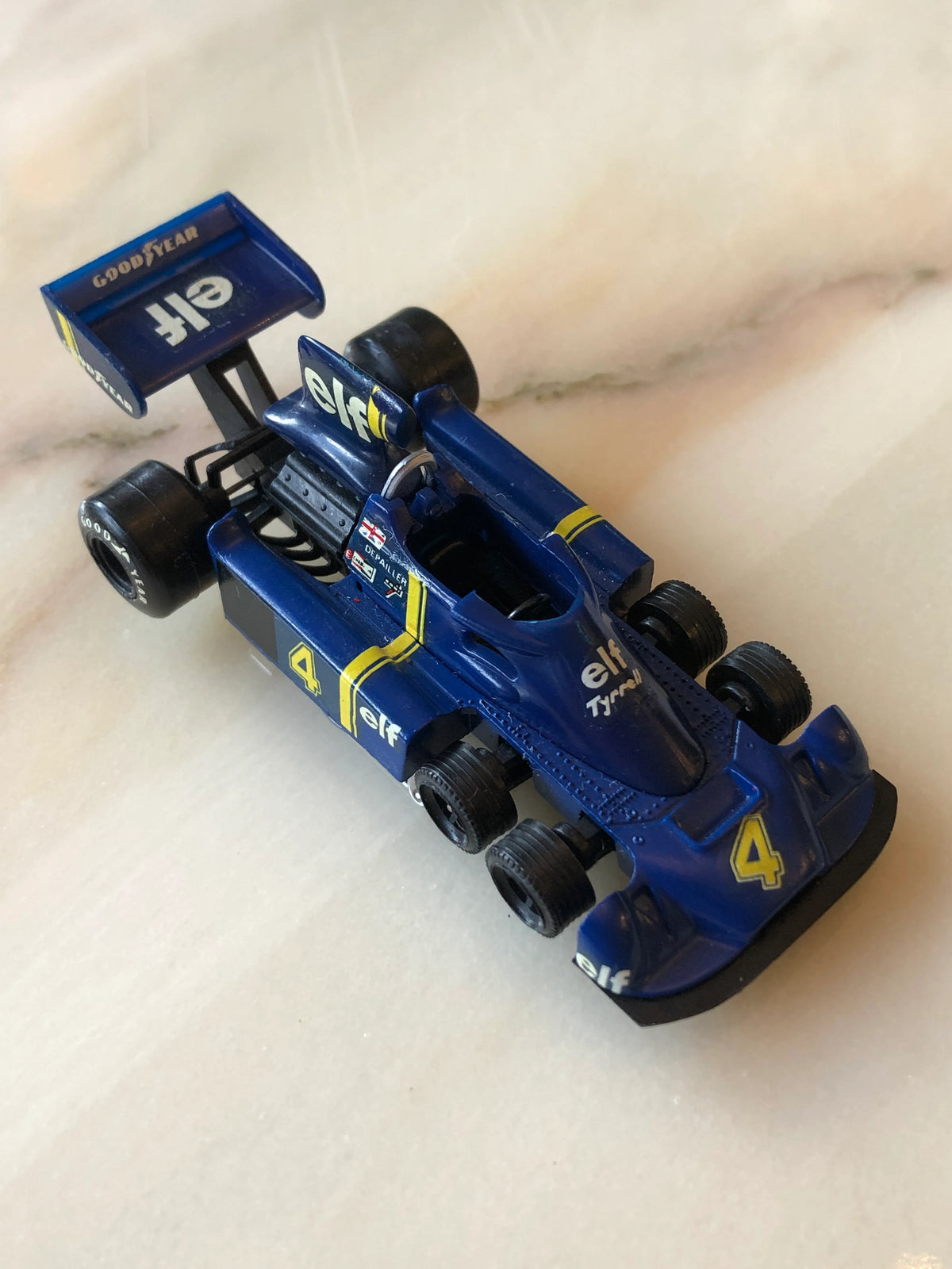Broochella Men's Blu Tyrrell No.4 Vintage Formula One Racing Car Brooch, featuring a navy blue six-wheeled race car with yellow stripes, number 4 decals, Elf and Goodyear branding, and a distinctive rear wing.