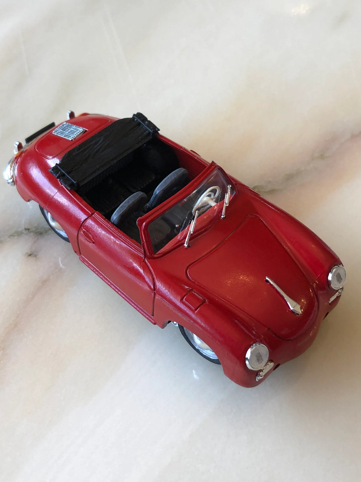 Broochella Men's Rosso Cabrio No.356 Vintage Convertible Car Brooch in glossy red, featuring a classic open-top sports car design, black folded roof, dark interior, chrome headlights and silver detailing.