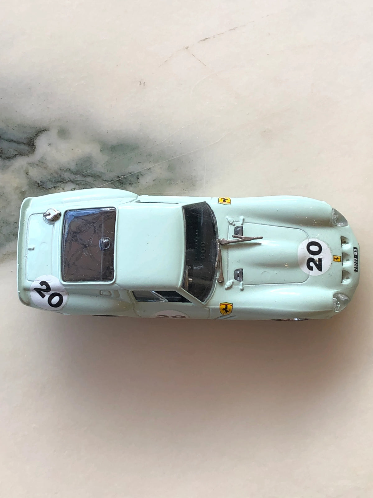 Broochella Men's Verde Acqua No.20 Vintage Ferrari Racing Car Brooch photographed from above, showcasing its pale aqua green body, number 20 decals, Ferrari badges, sculpted bonnet, dark windscreen and rear window.