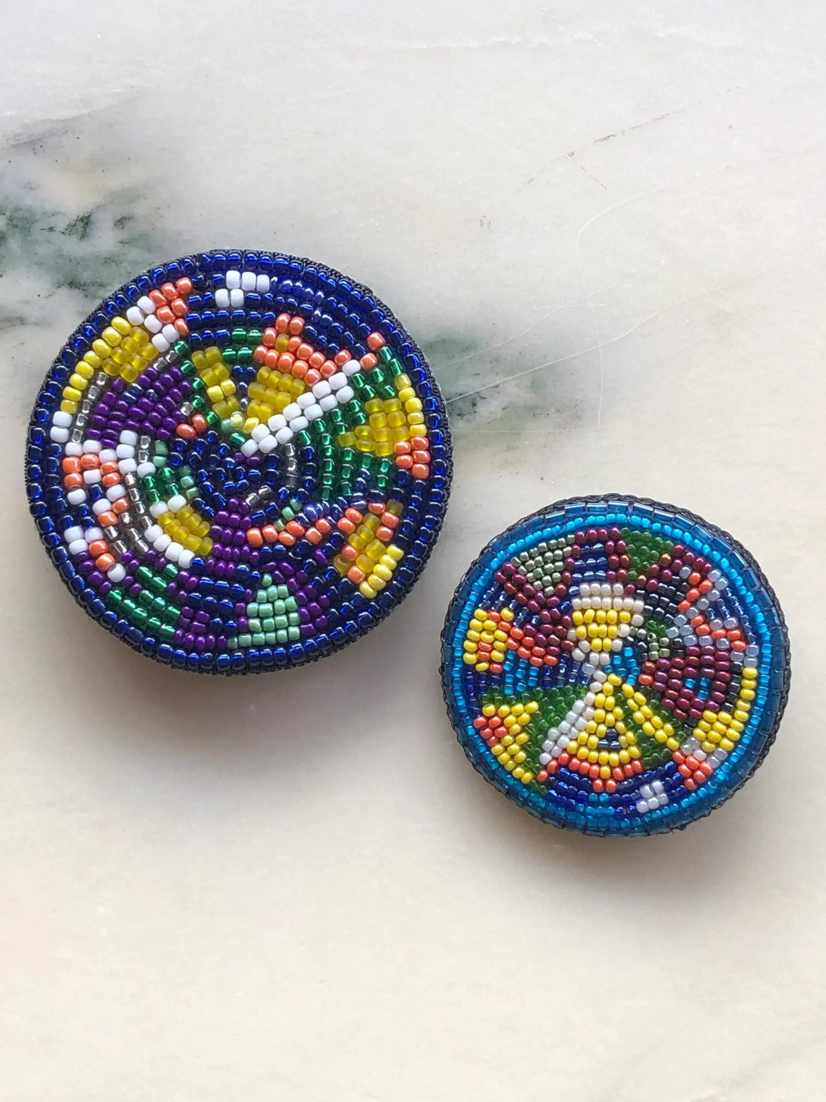 Broochella Men’s Viva La Gioia Brooch in large and small sizes, featuring colourful hand-beaded designs, photographed together on a white marble background.