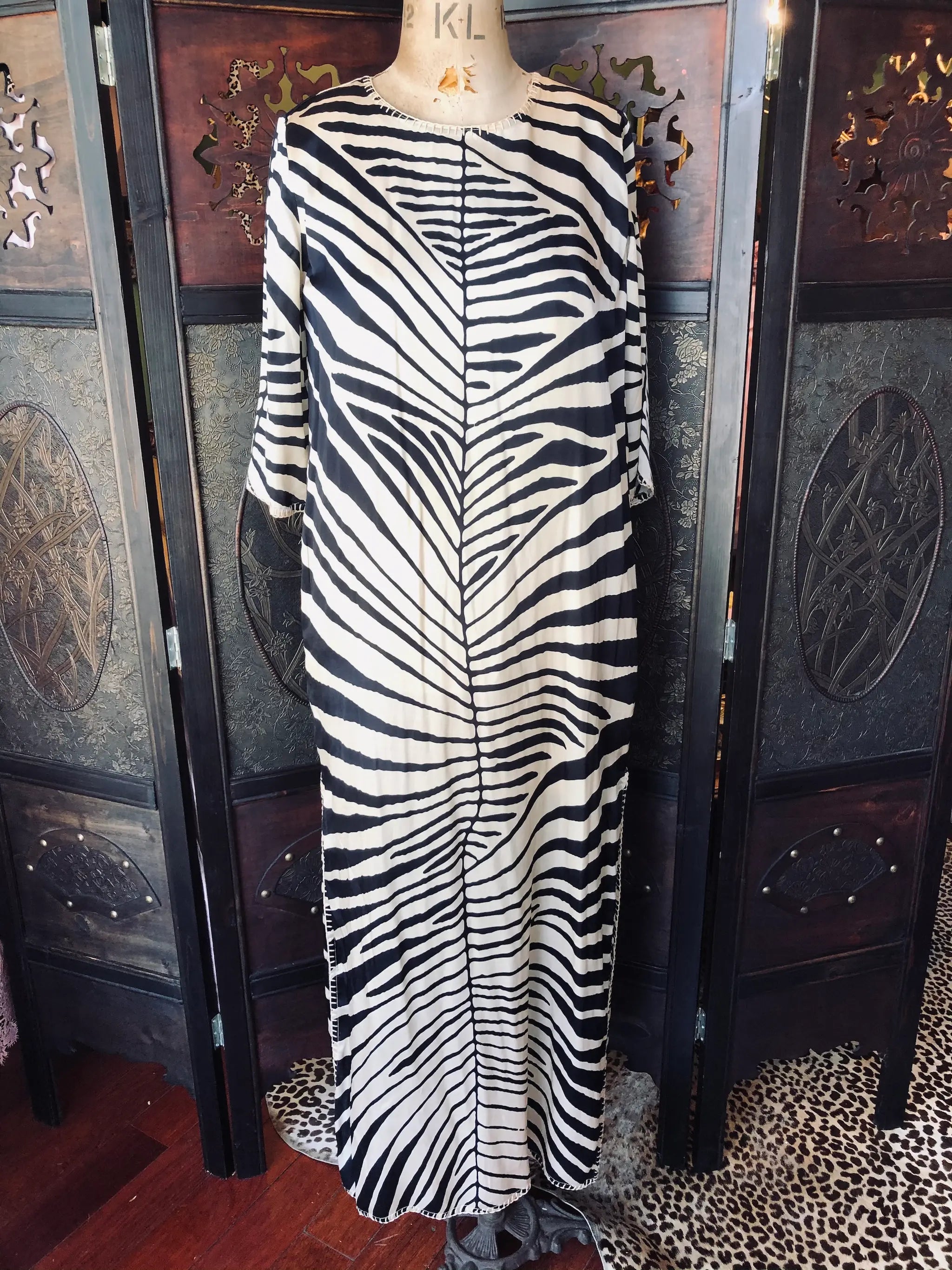 Broochella Michonet silk Zebra-striped dress on a mannequin against a decorative wall.