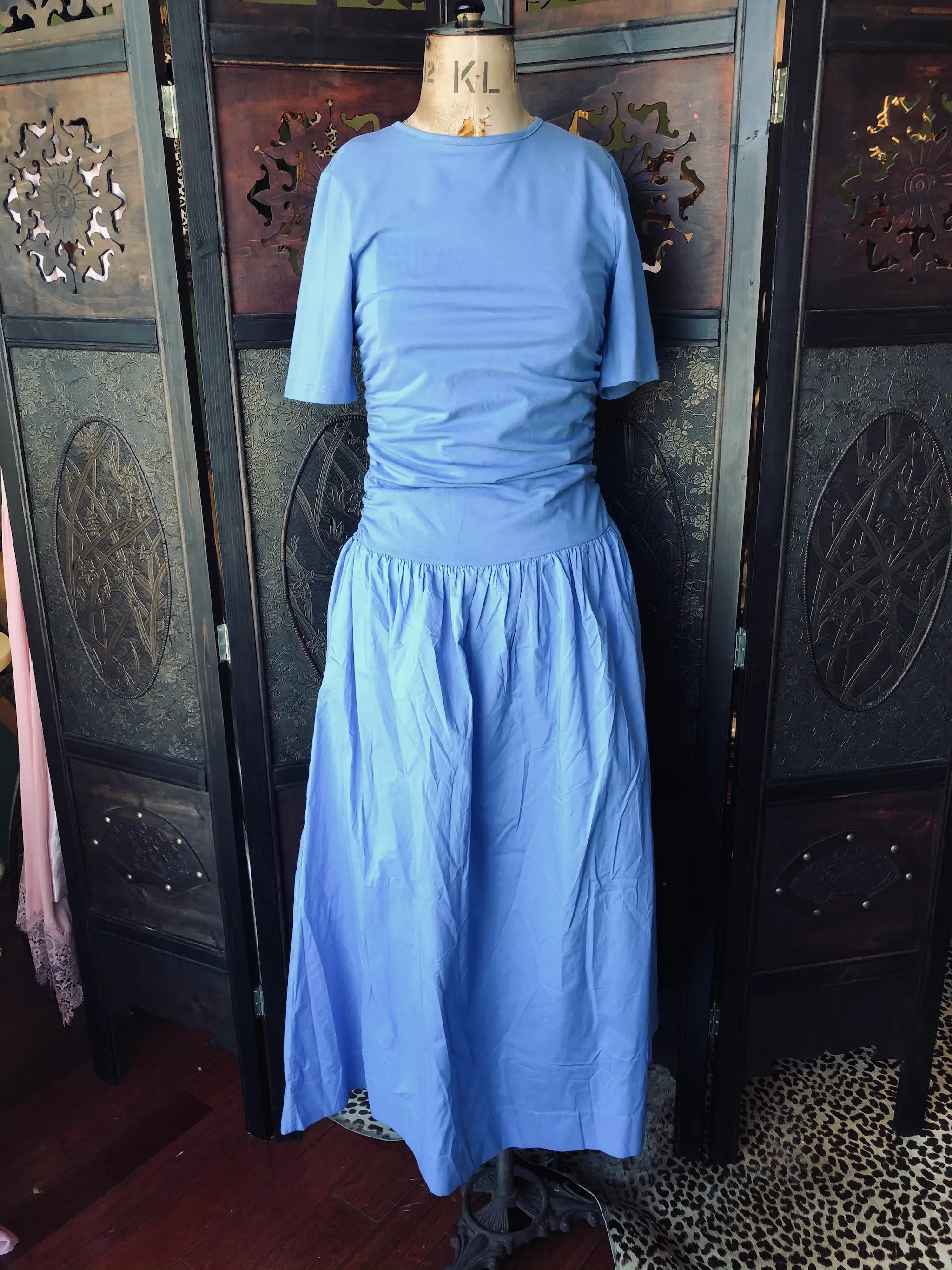 Broochella Never Fully Dresses blue cotton dress. It is pictured Mannequin against a decorative wall.