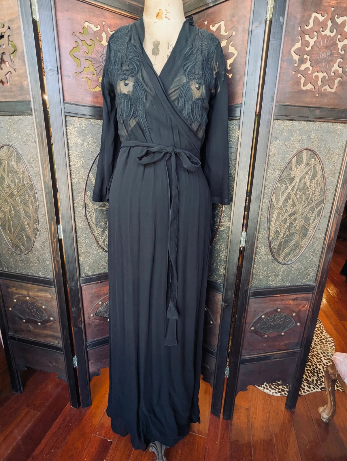 Broochella Nü Denmark size small Long sheer black dress with embroidered lace detailing on a mannequin against a decorative screen.