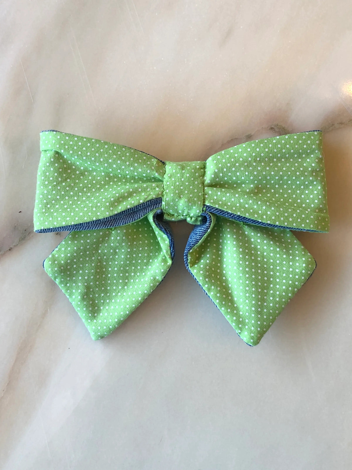 Broochella Poochella Pet Bow in fresh green cotton with tiny white polka dots, featuring a structured bow design, pointed tails and contrasting blue denim edging.