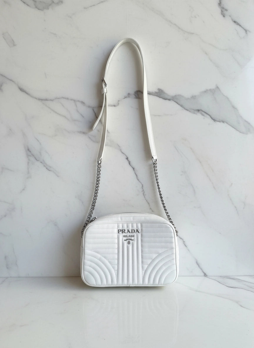 Broochella White authentic leather Prada designer camera bag purse on a white marble background