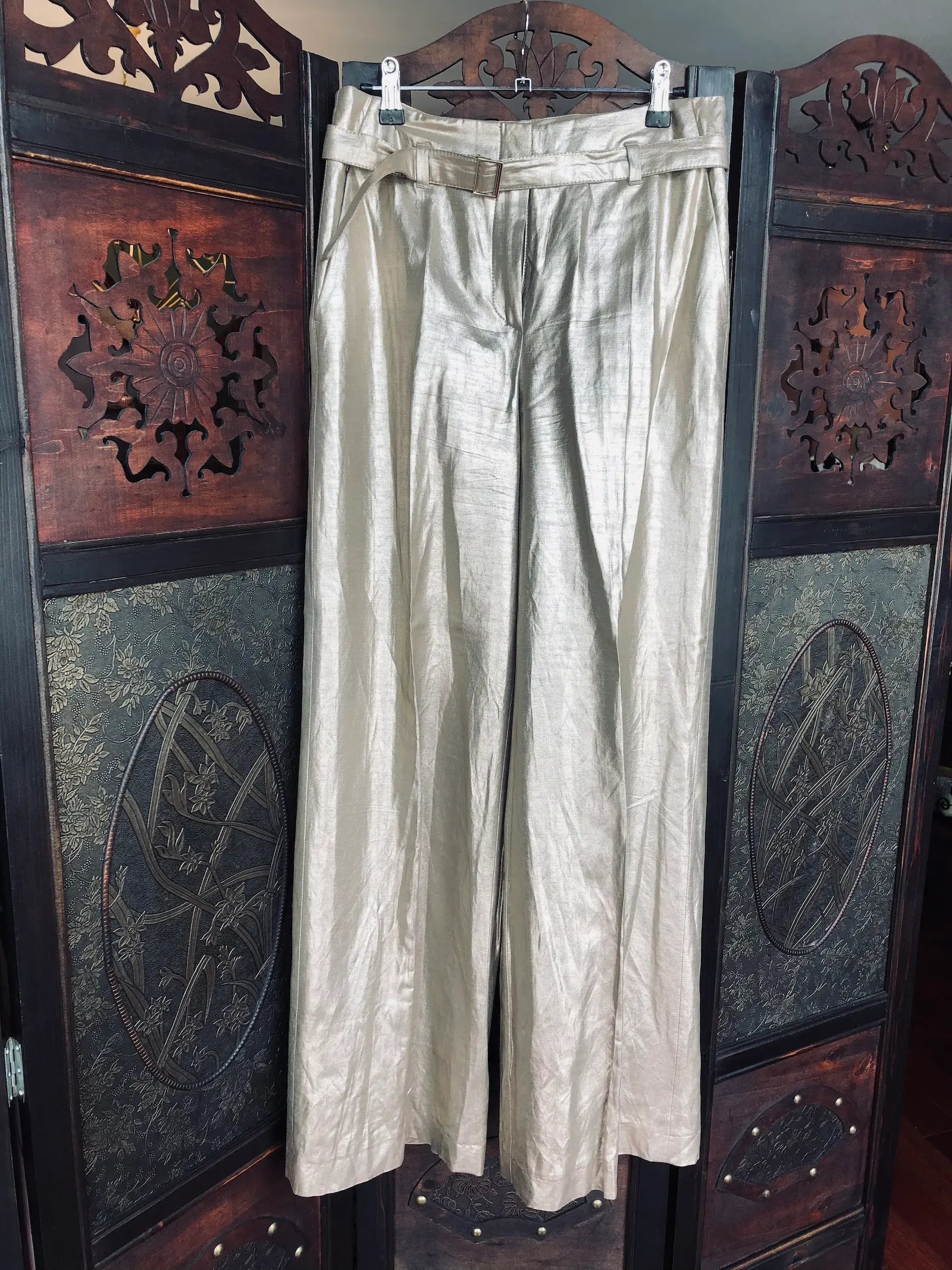 Broochella The Stylist's Closest Raffaello Rossi gold, linen trousers. They are hanging on an ornate, dark wood room divider. 