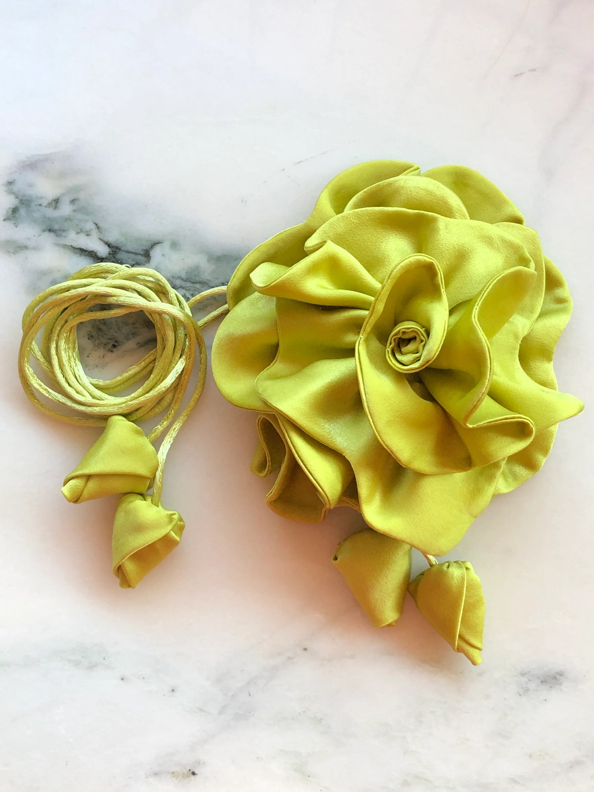Broochella Rosetta chartreuse flower choker and brooch with matching tie cords and fabric buds, photographed on white marble with grey veining.