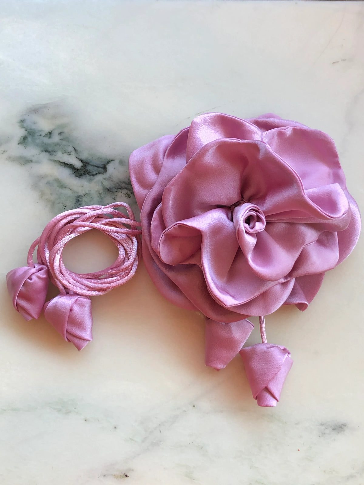 Broochella Rosetta pink flower choker and brooch with soft sculptural petals, matching tie cords and fabric buds, photographed on white marble with grey veining.